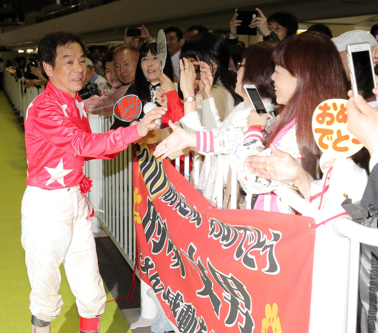 11R、地方通算7000勝を達成した的場騎手は祝福横断幕の前でファンと握手を交わす（撮影・松本俊）
