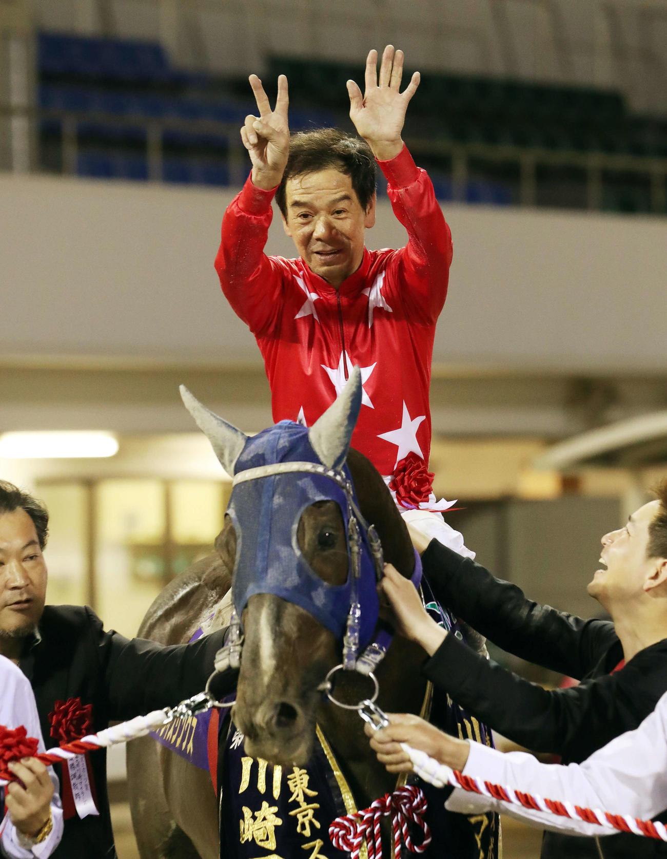 地方通算7000勝を達成した的場文男騎手は両手で「7」をつくって記念撮影を行う