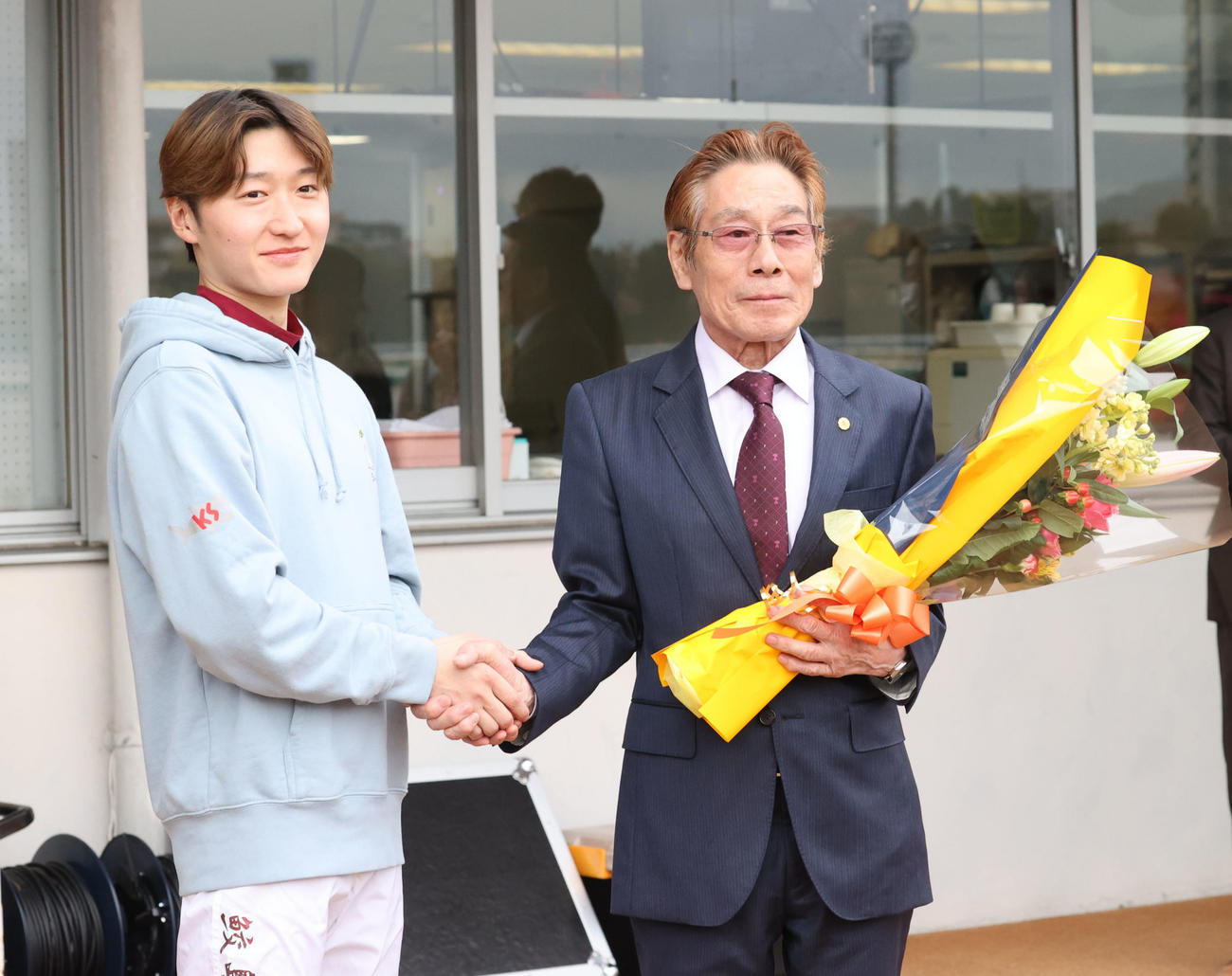 2日、定年引退する河内洋調教師（右）は鮫島克駿騎手に花束を贈られ笑顔を見せる