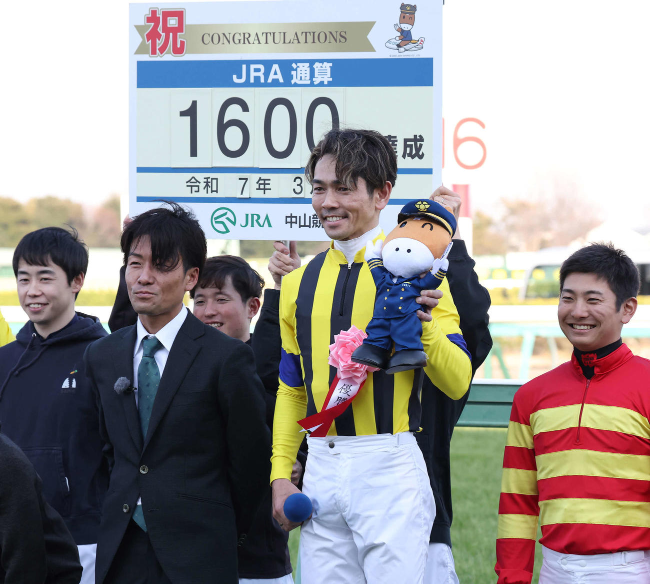 JRA通算1600勝を達成し笑顔を見せる戸崎騎手。左は元騎手の森氏（撮影・丹羽敏通）