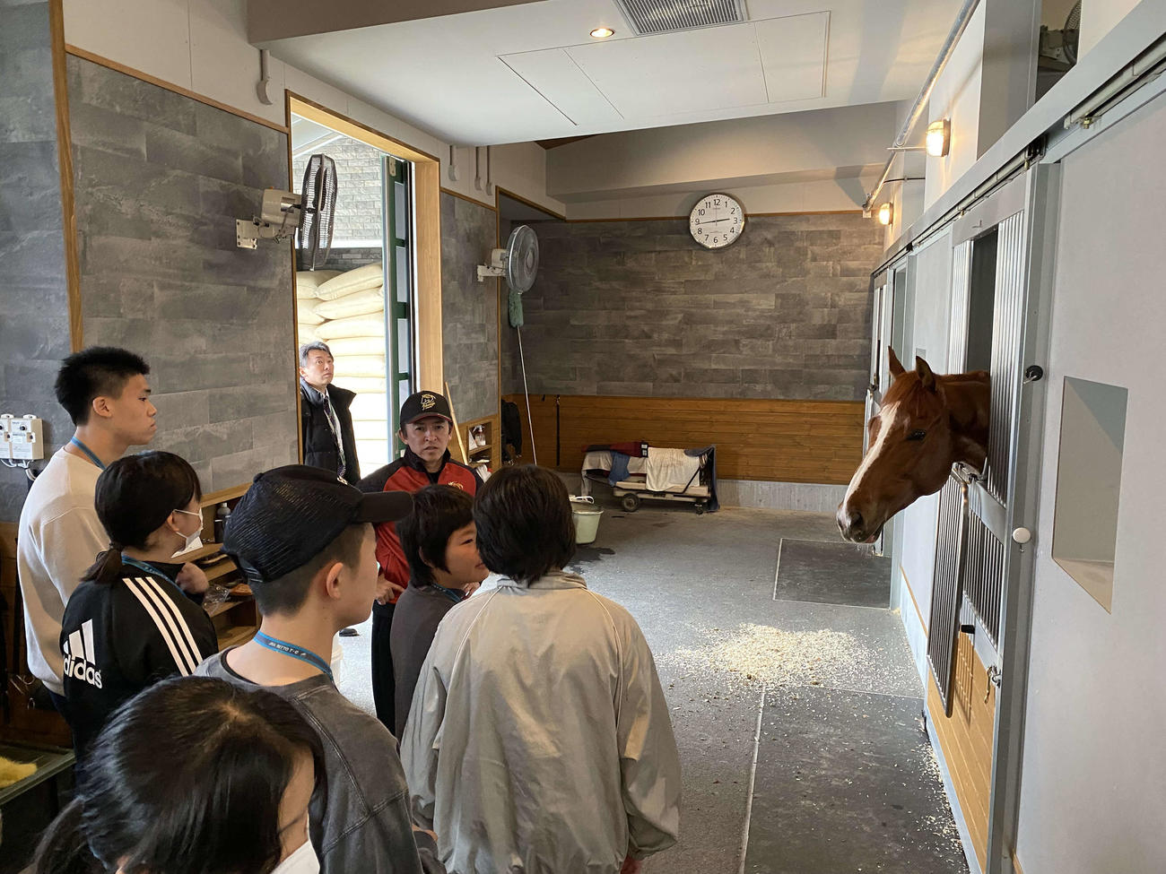 トレセン職場見学ツアーで福永厩舎を訪れた中学生と、引率する福永師（JRA提供）