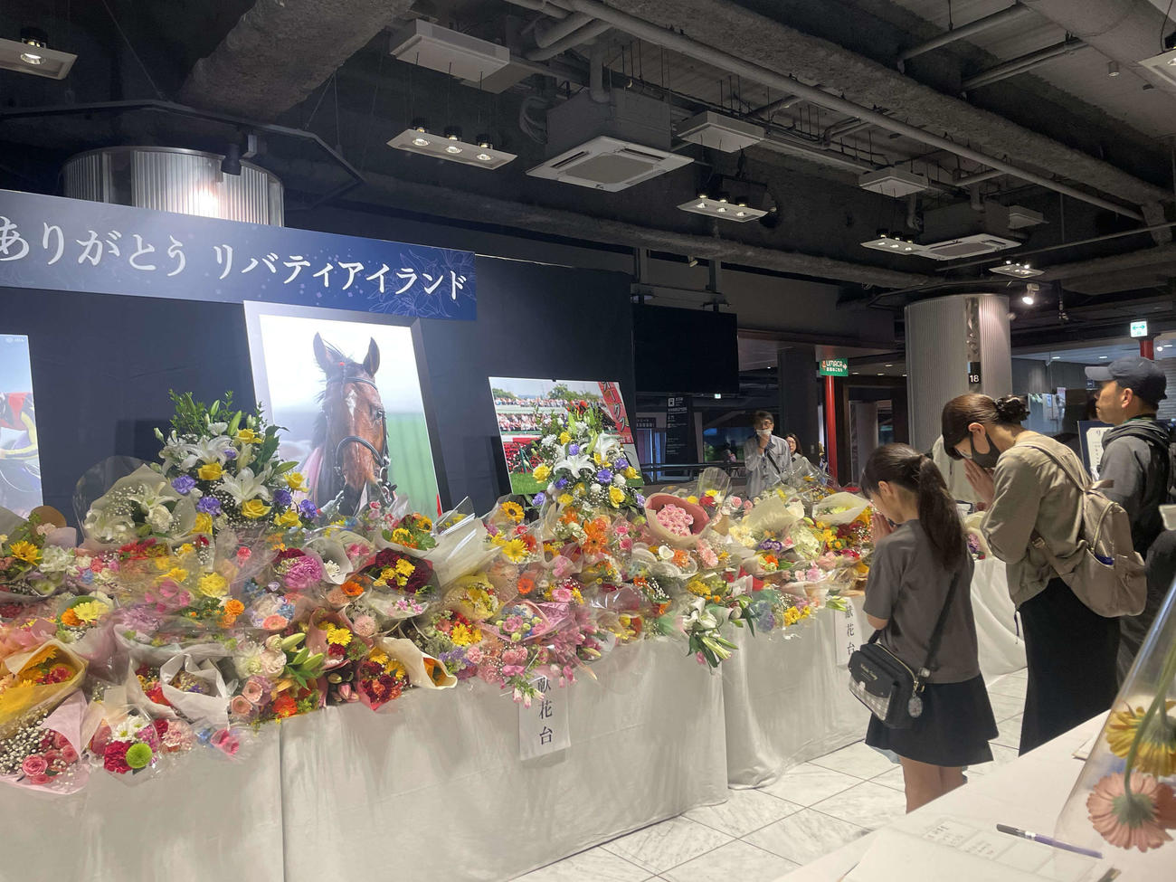 リバティアイランドの献花台の前で手を合わせるファン