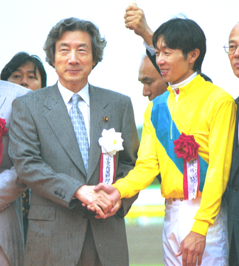 2002年5月26日、小泉純一郎首相（当時＝左）は表彰式で優勝馬タニノギムレットの武豊騎手と握手