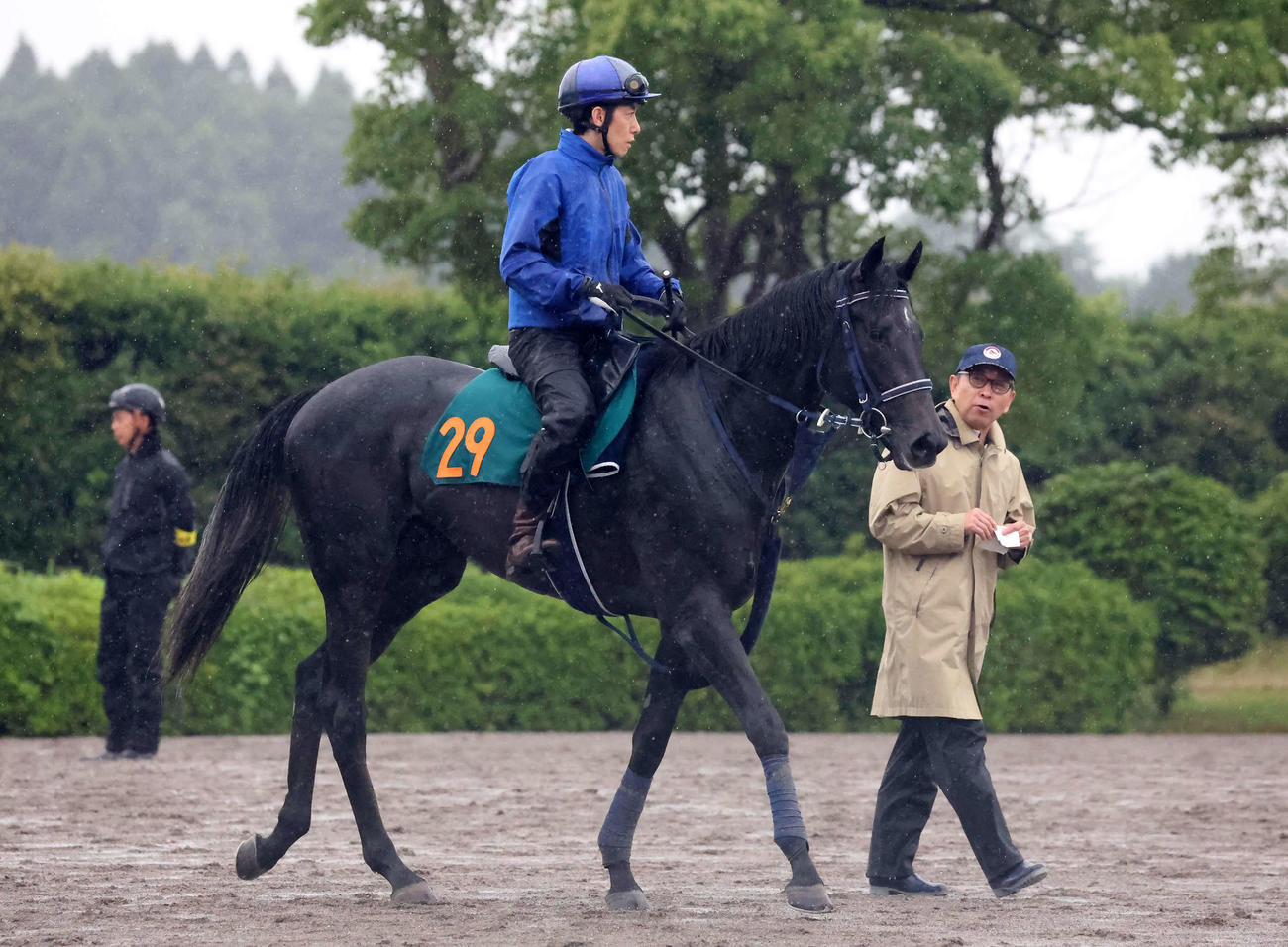 調教を終えて馬場を出るリアライズシリウスと津村騎手。右は手塚師（撮影・丹羽敏通）