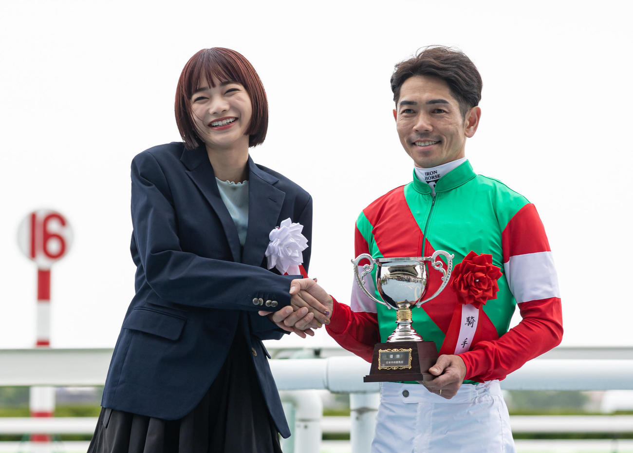 プレゼンターの見上愛と笑顔で握手する戸崎騎手（撮影・村野早祐）