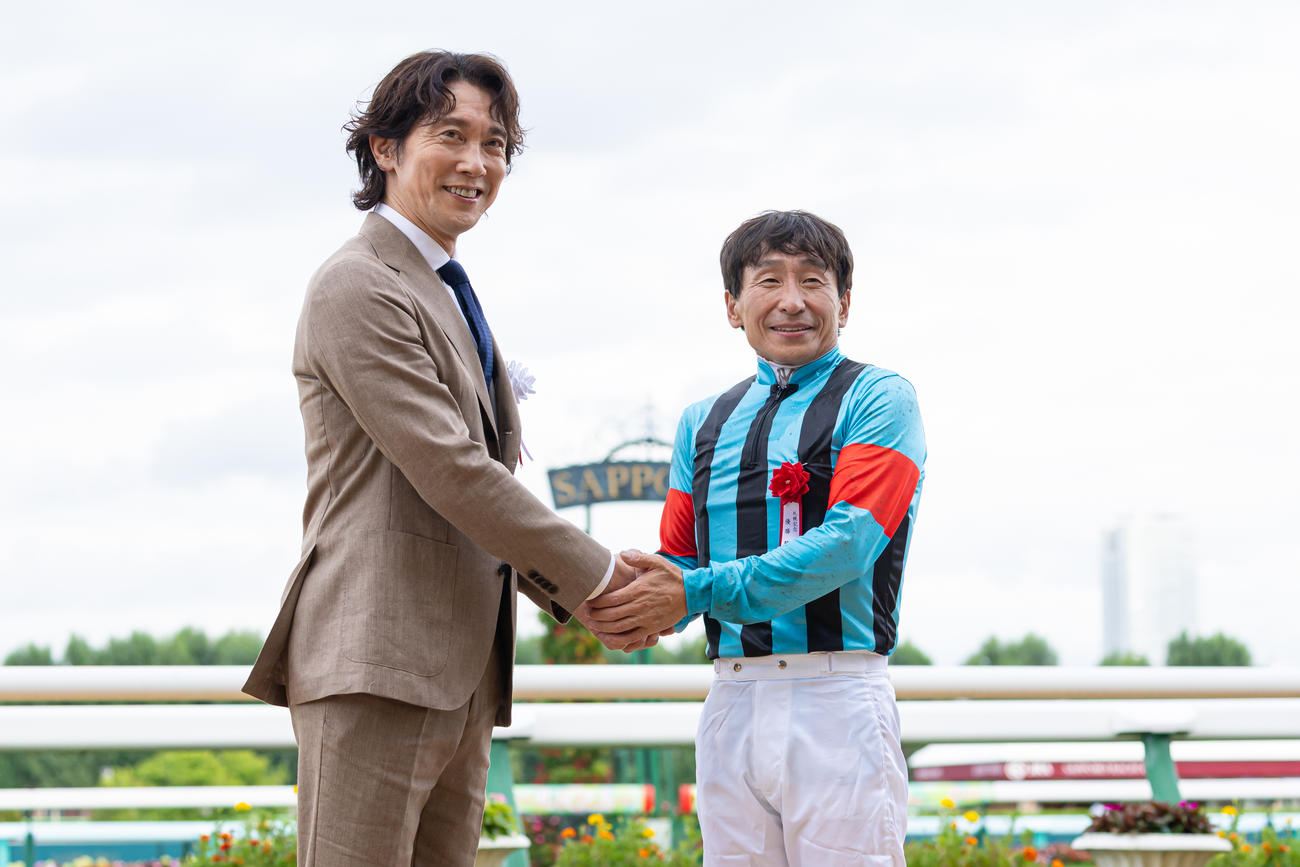 ゲストプレゼンターの佐々木蔵之介と握手する横山典騎手（撮影・村野早祐）