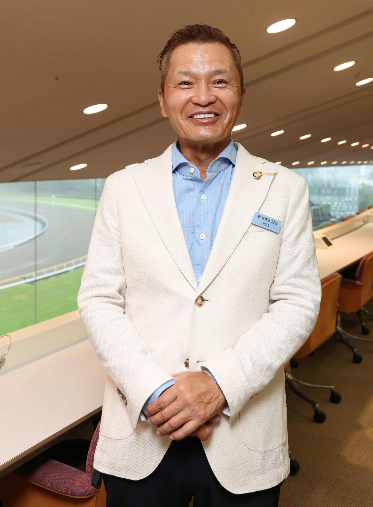 笑顔で写真に納まる佐野信幸オーナー（撮影・丹羽敏通）