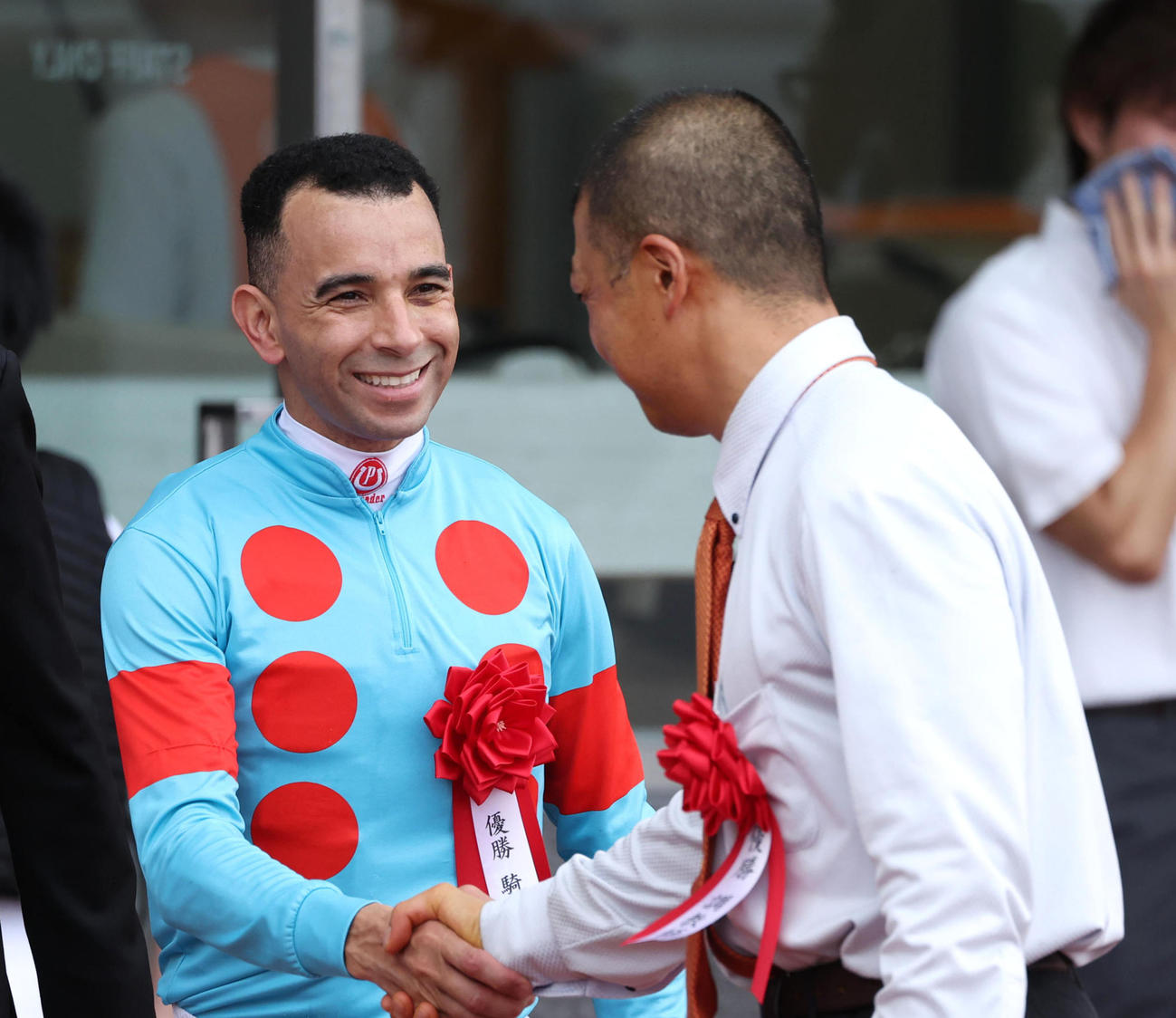 笑顔で握手をするモレイラ騎手（左）と高野師（撮影・白石智彦）
