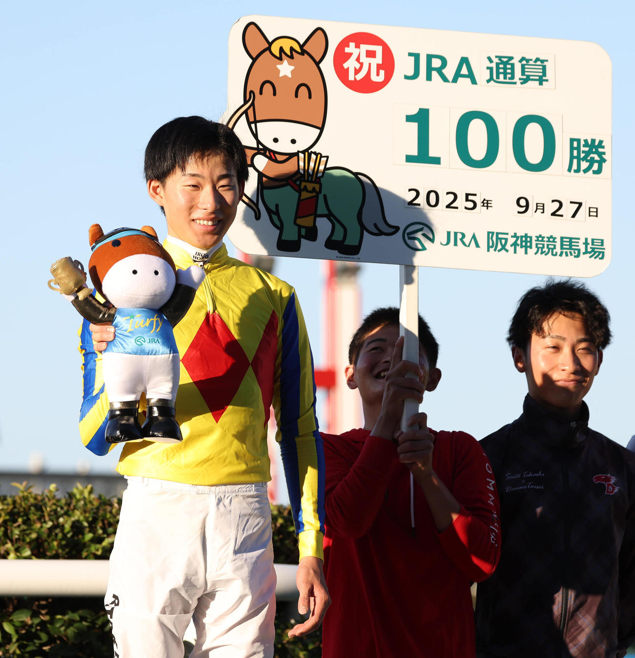 阪神12R、JRA通算100勝を達成して笑顔で記念写真に納まる高杉騎手（左）（撮影・白石智彦）