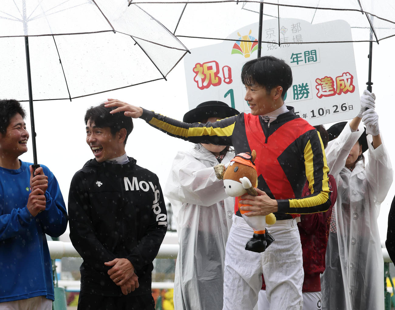 記念写真に並んだ戸崎騎手（中央）の頭をなでるJRA年間100勝を達成した坂井騎手（撮影・白石智彦）