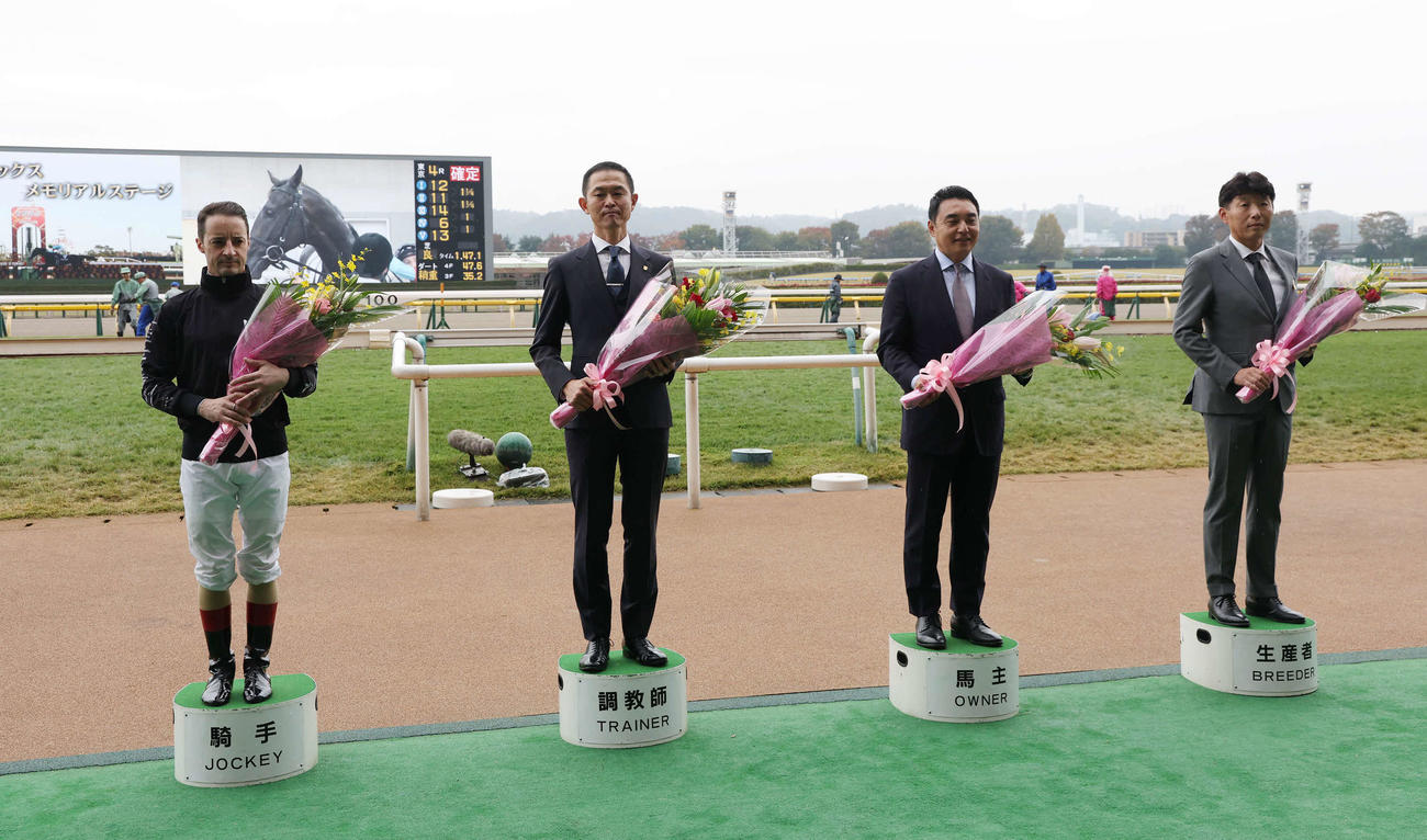 写真に納まる、左からルメール騎手、木村哲也調教師、シルクレーシングの米本昌史代表、吉田俊介氏