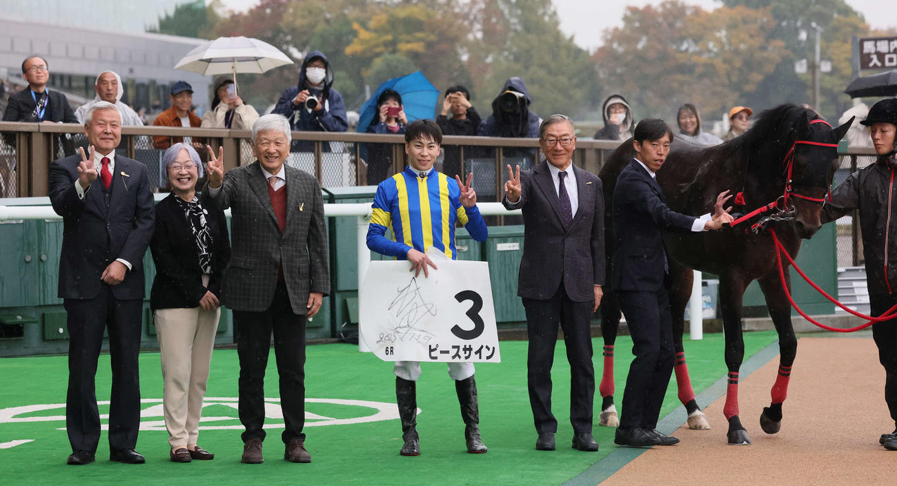 東京6R、2歳新馬戦を制したピースサインの口取りで「ピースサイン」で写真に納まる横山武騎手と関係者（撮影・丹羽敏通）