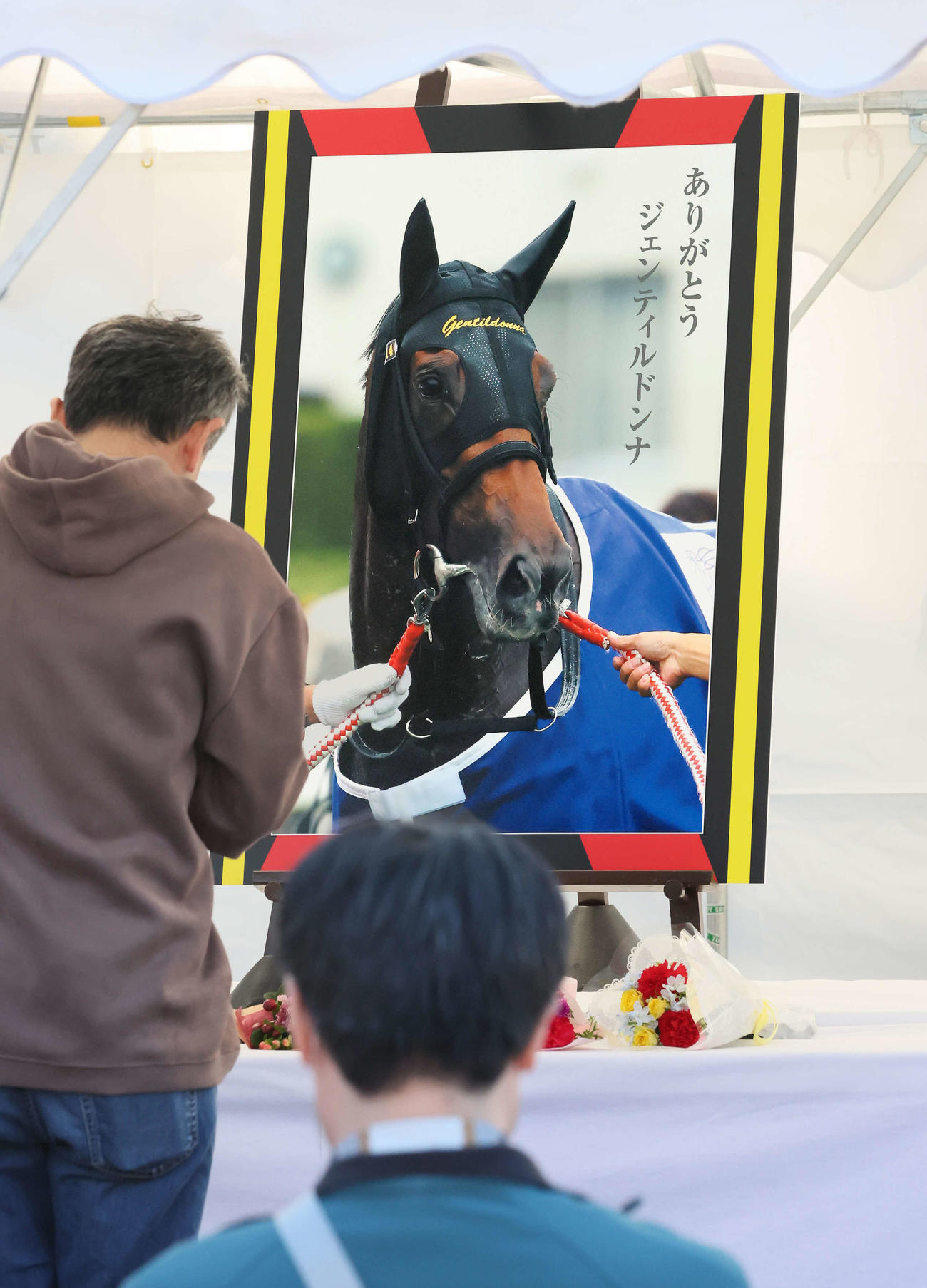 ジェンティルドンナの献花台で手を合わせる人（撮影・丹羽敏通）