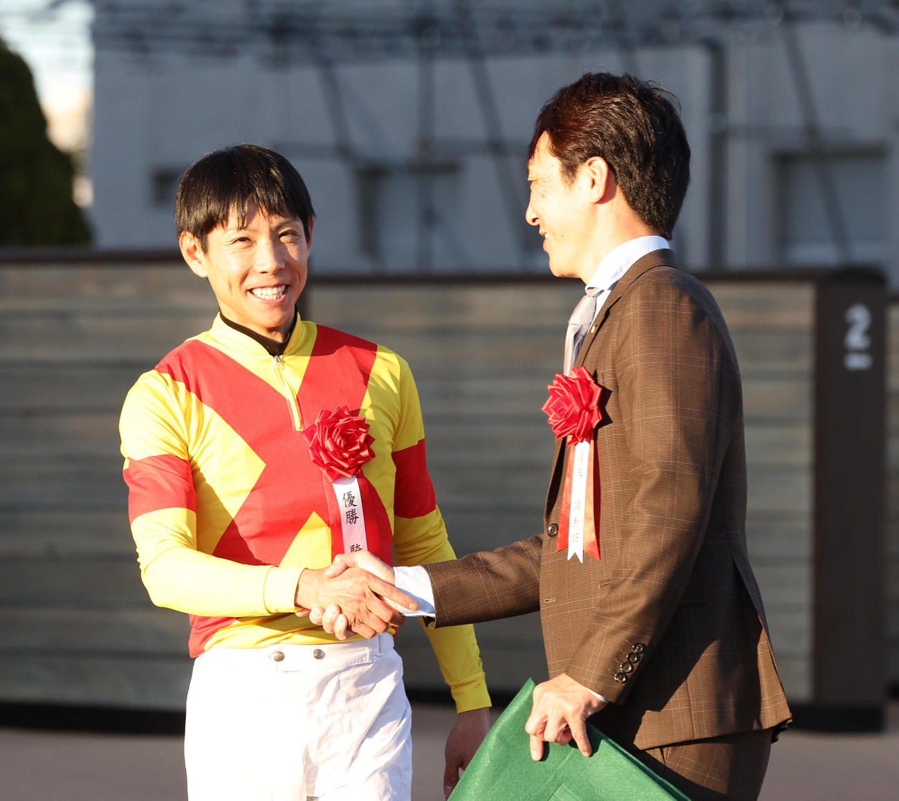 笑顔で握手する北村友一騎手と吉岡師（撮影・白石智彦）
