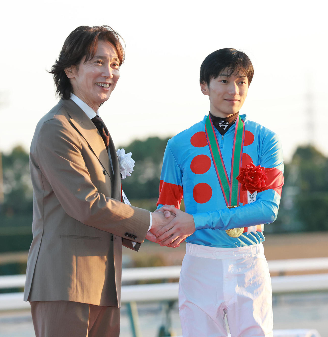 チャンピオンズCを制した坂井騎手（右）はプレゼンターの佐々木蔵之介と握手を交わす（撮影・上田博志）