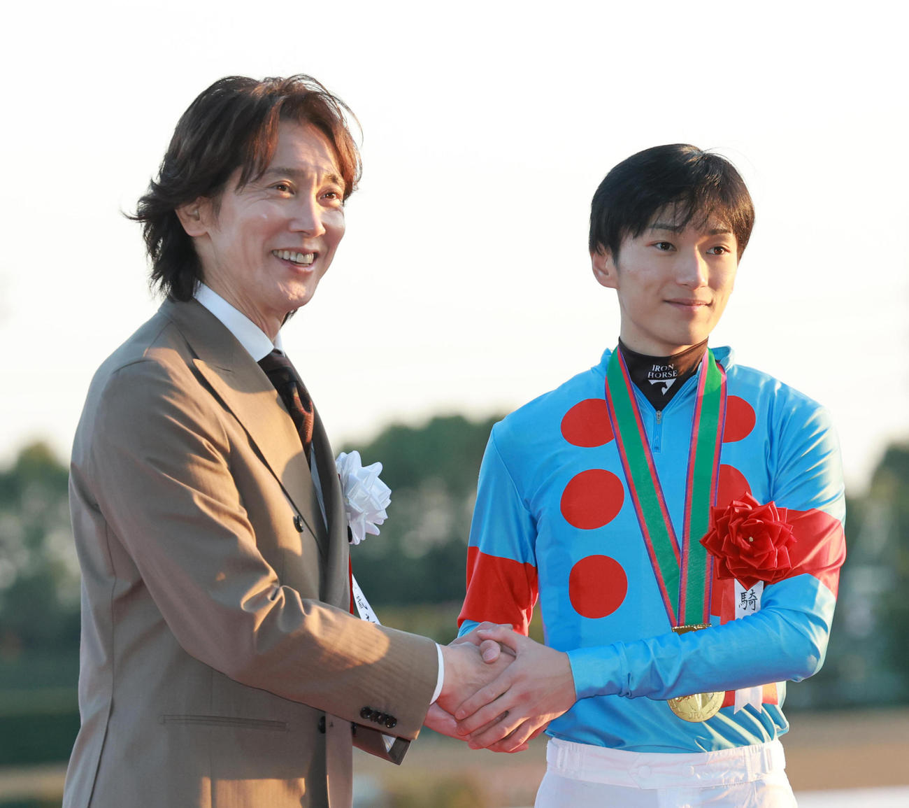 チャンピオンズCを制した坂井騎手（右）はプレゼンターの佐々木蔵之介と握手を交わす（撮影・上田博志）