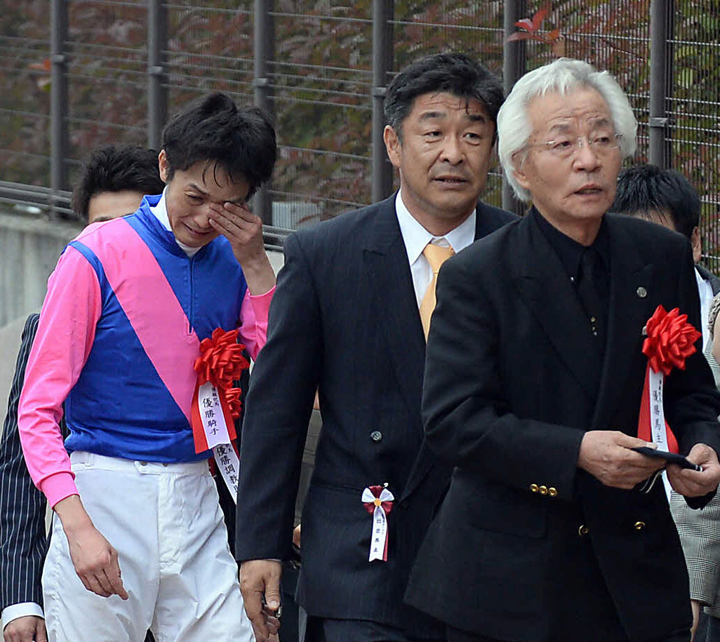 目頭を押さえながら表彰式に向かう武幸四郎騎手と松本好雄オーナー