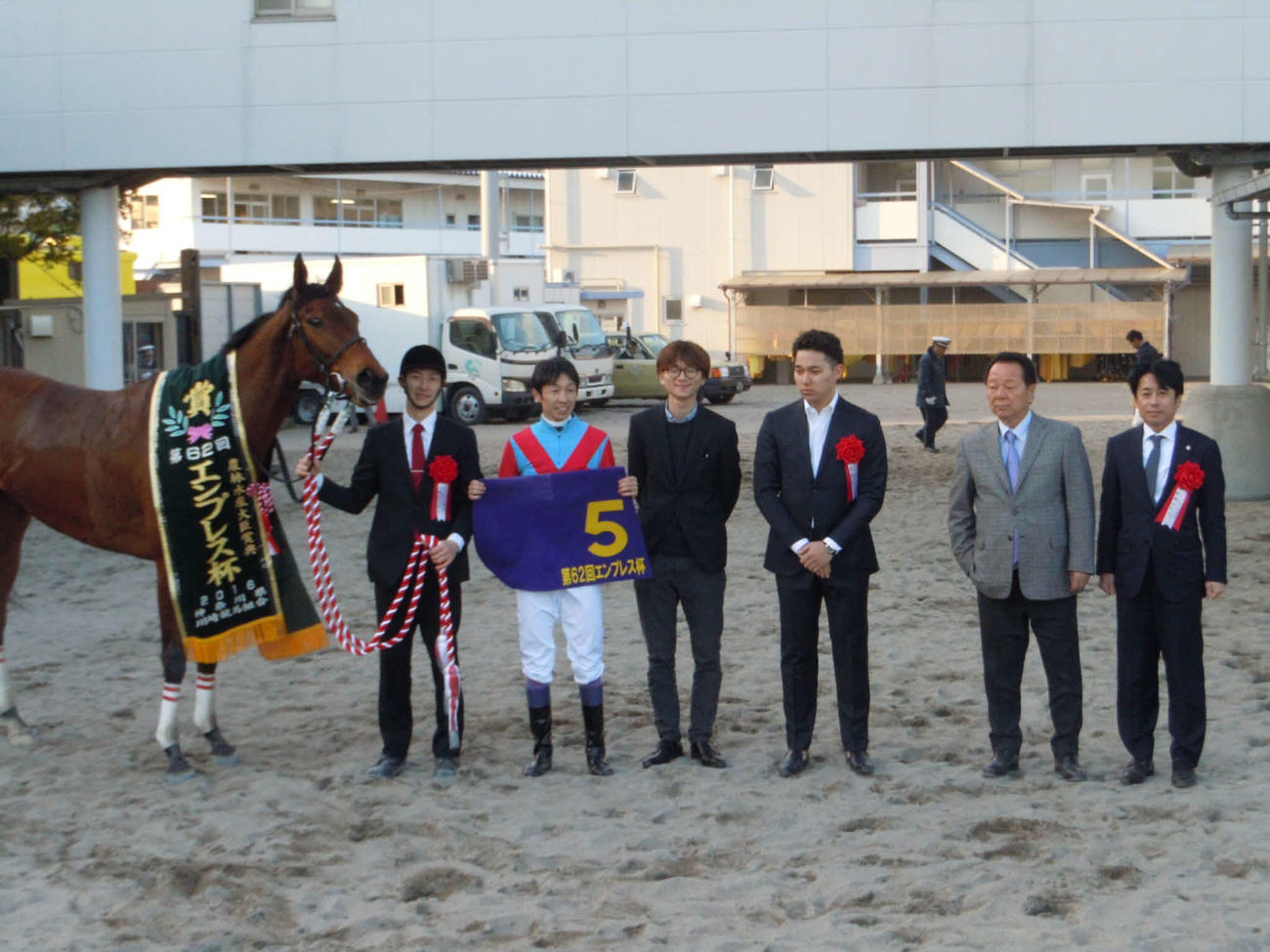 2016年3月、人気に応えエンプレス杯を連覇、重賞4勝目を挙げたアムールブリエ。笑顔でゼッケンを持つ武豊騎手。右端は松永幹師
