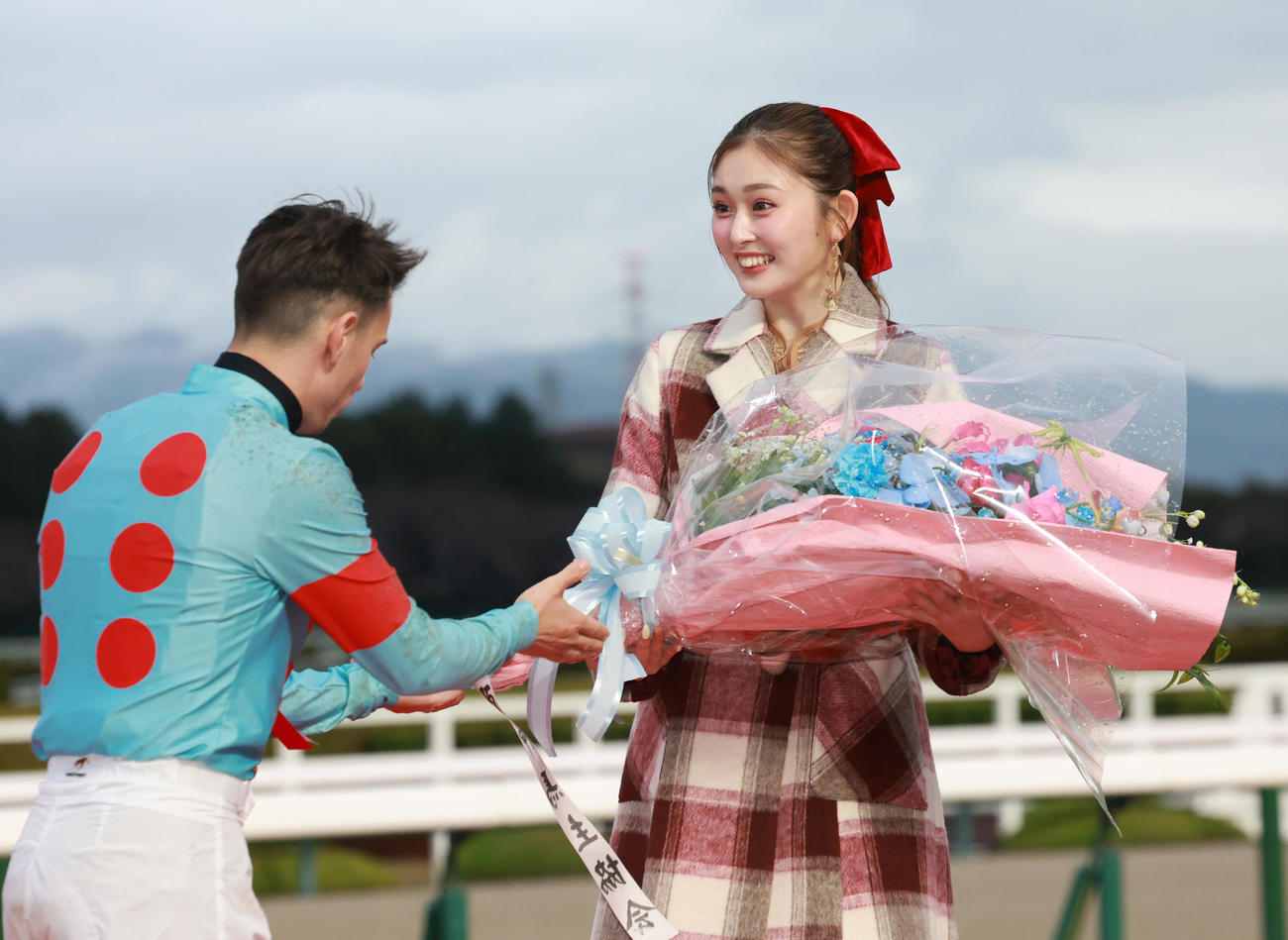 朝日杯FSを制したC・デムーロ騎手（左）から花束を受け取り笑顔を見せるゆうちゃみ（撮影・上田博志）