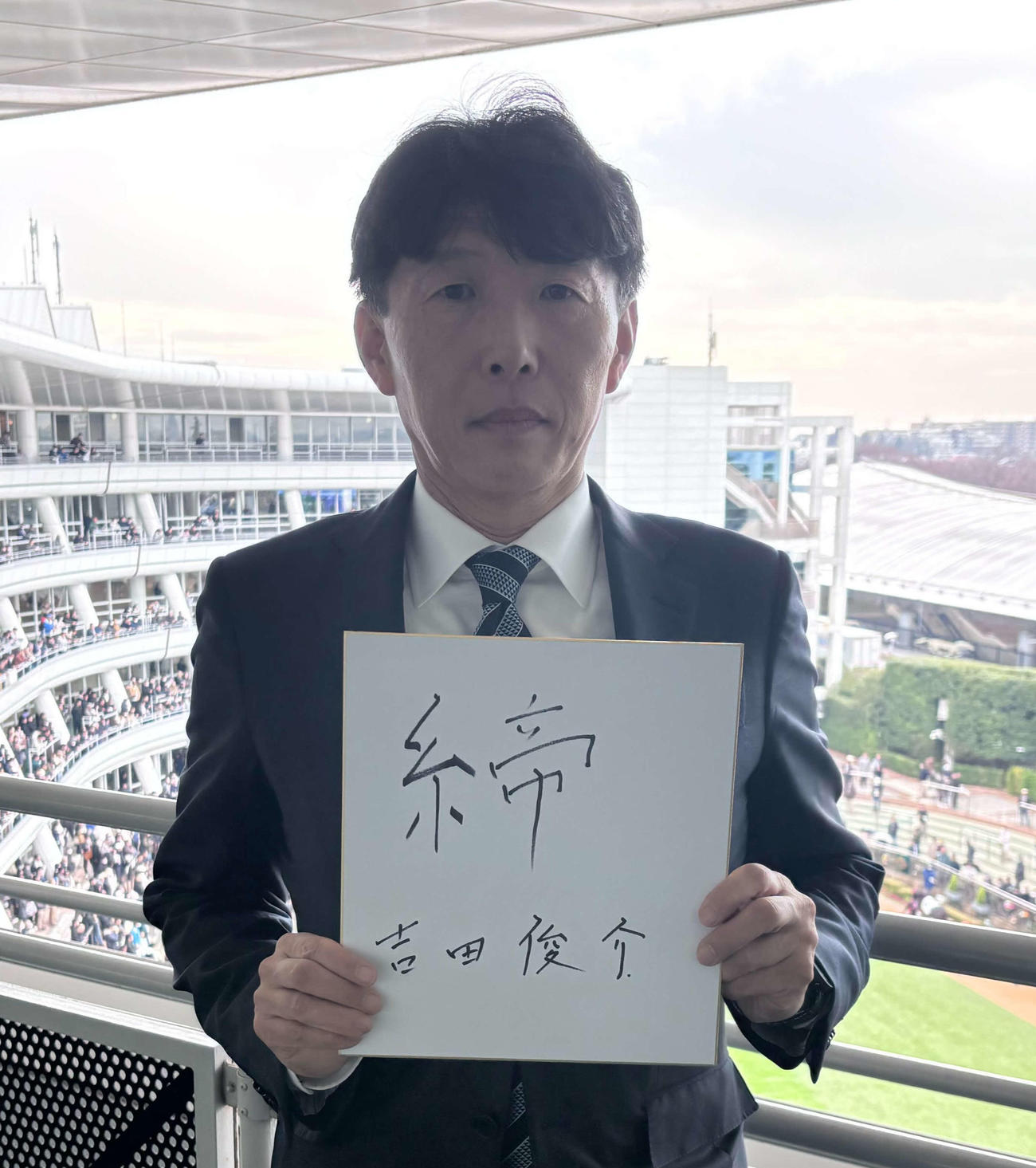 「締」と書いた色紙を手にするサンデーR吉田俊介代表