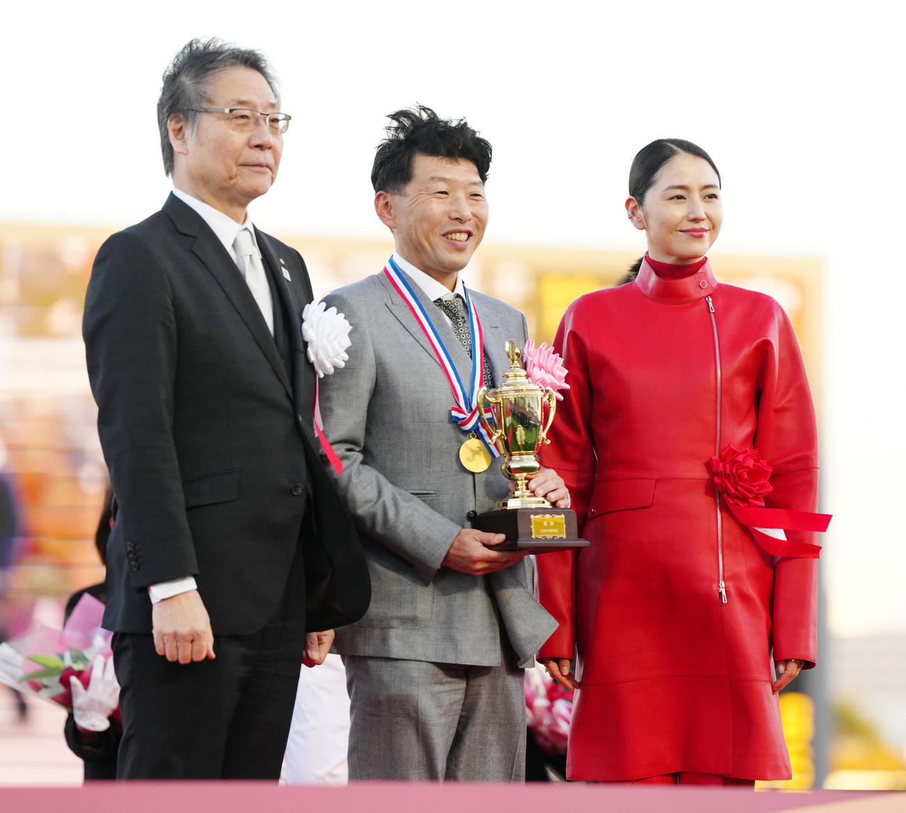 24年12月、有馬記念をレガレイラで制し写真に納まる吉田俊介代表（中央）。右はプレゼンター長澤まさみ