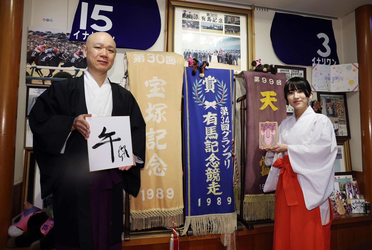「午」と記した穴守稲荷神社の宮司の井上直洋さん（左）と自身がデザインした御朱印帳を手にする巫女の菊竹夏希さん（撮影・宮地輝）