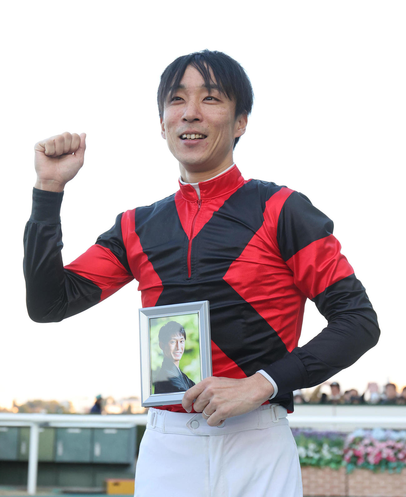 引退セレモニーで藤岡康騎手の遺影を持ってガッツポーズする田中騎手（撮影・白石智彦）