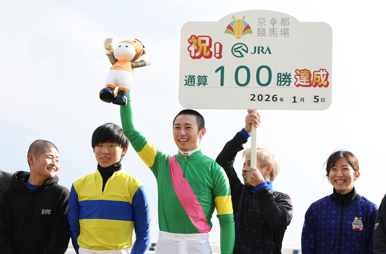 京都5RでJRA通算100勝を達成して高々とターフィー人形を掲げる吉村騎手（中央）（撮影・白石智彦）