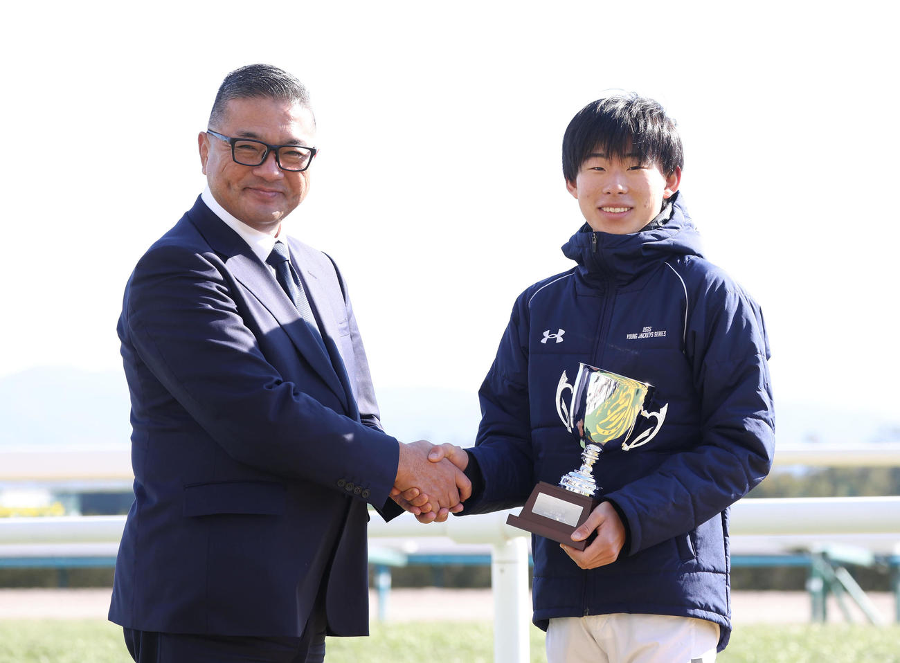 握手して記念写真に納まる中央競馬騎手ホープ賞を受賞した高杉騎手（右）（撮影・白石智彦）