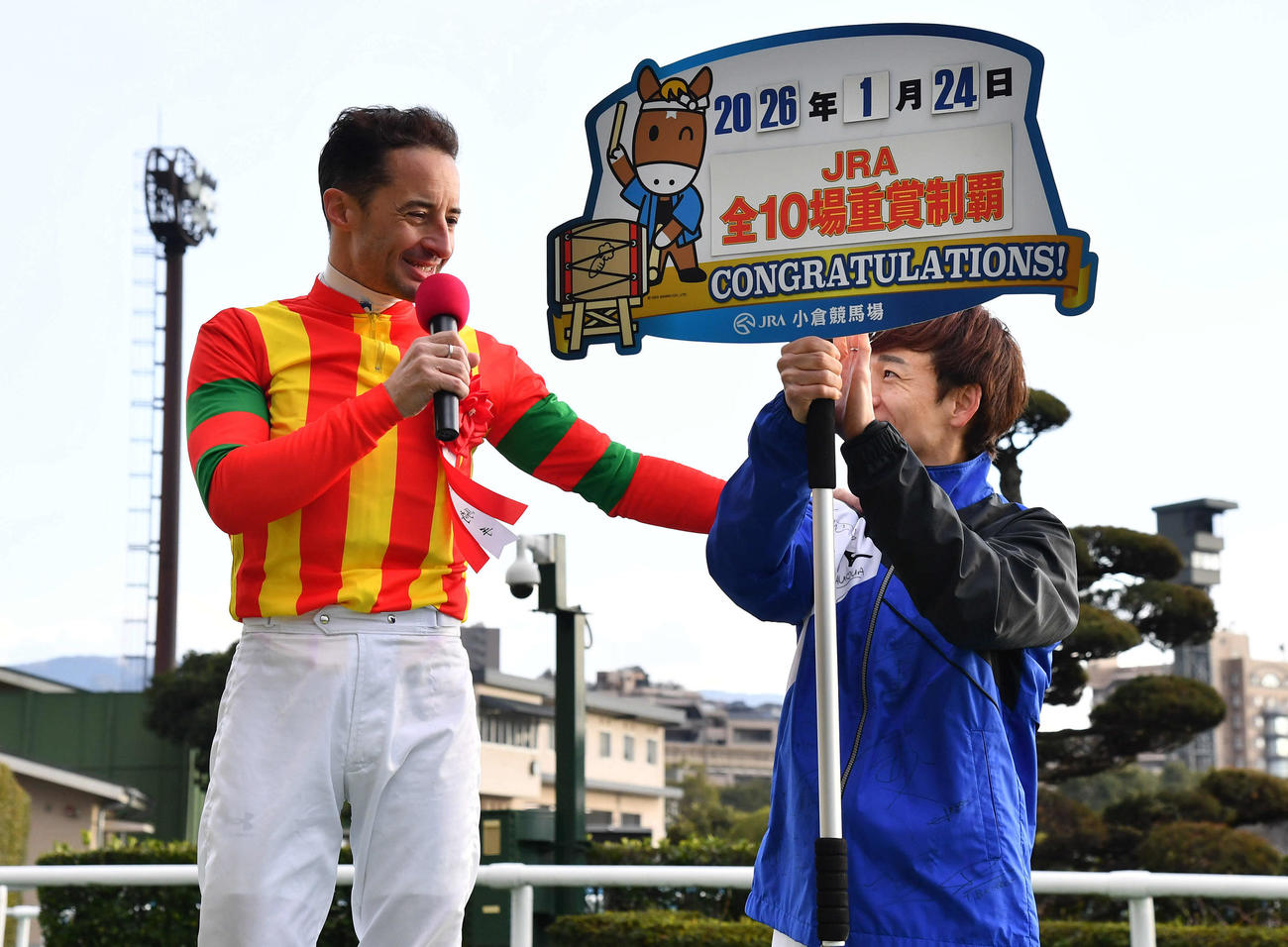 JRA全10場重賞制覇達成のルメール騎手はプラカードを持つ松山騎手に笑顔で声をかける（撮影・岩下翔太）