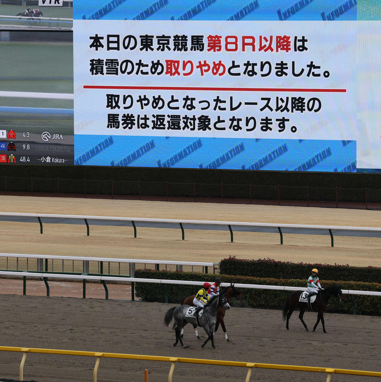 東京8R以降の取りやめを告げるターフビジョンと引き揚げる各馬（撮影・丹羽敏通）