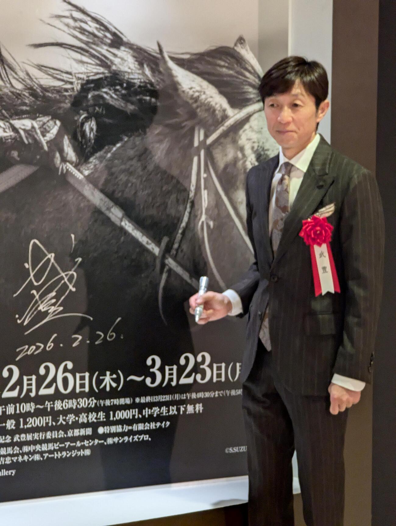 「武豊デビュー40年～前人未到の記録」のオープニングセレモニーでサインを書く武豊騎手