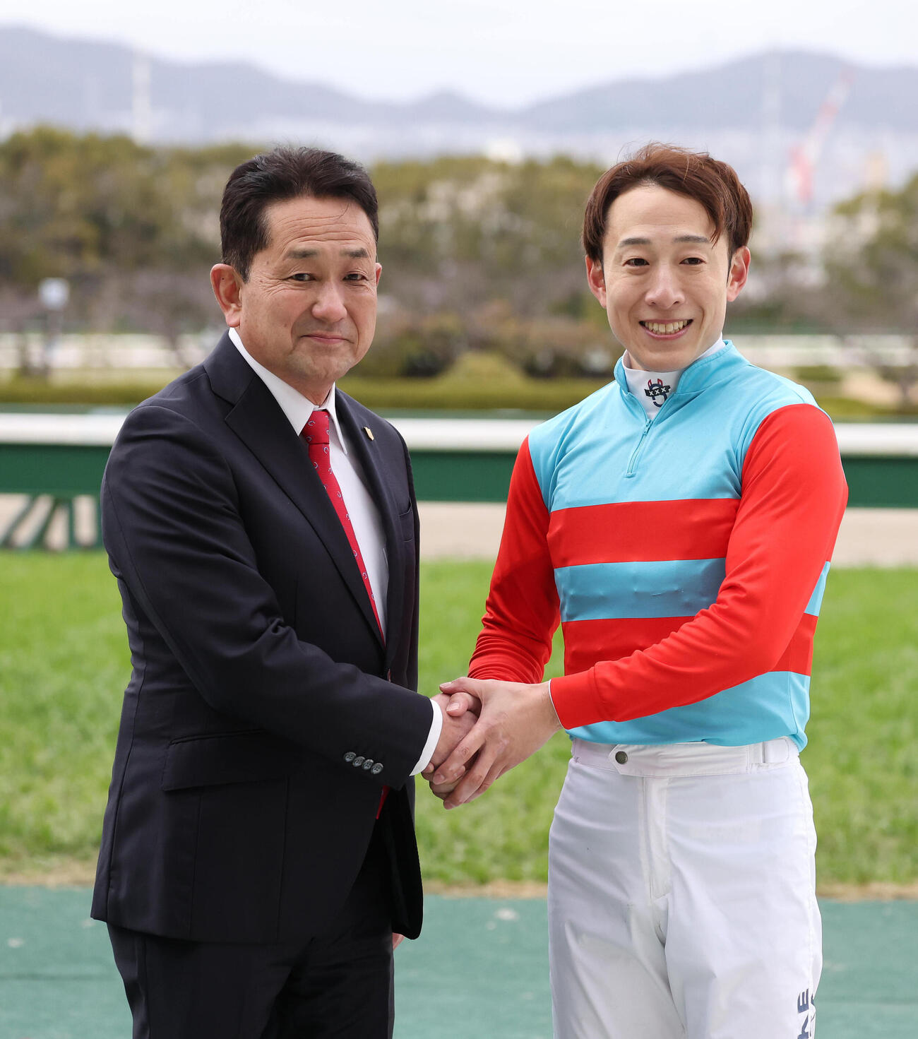 タマモイカロスでマーガレットSを制し父の藤岡師（左）と握手する藤岡佑騎手（撮影・白石智彦）