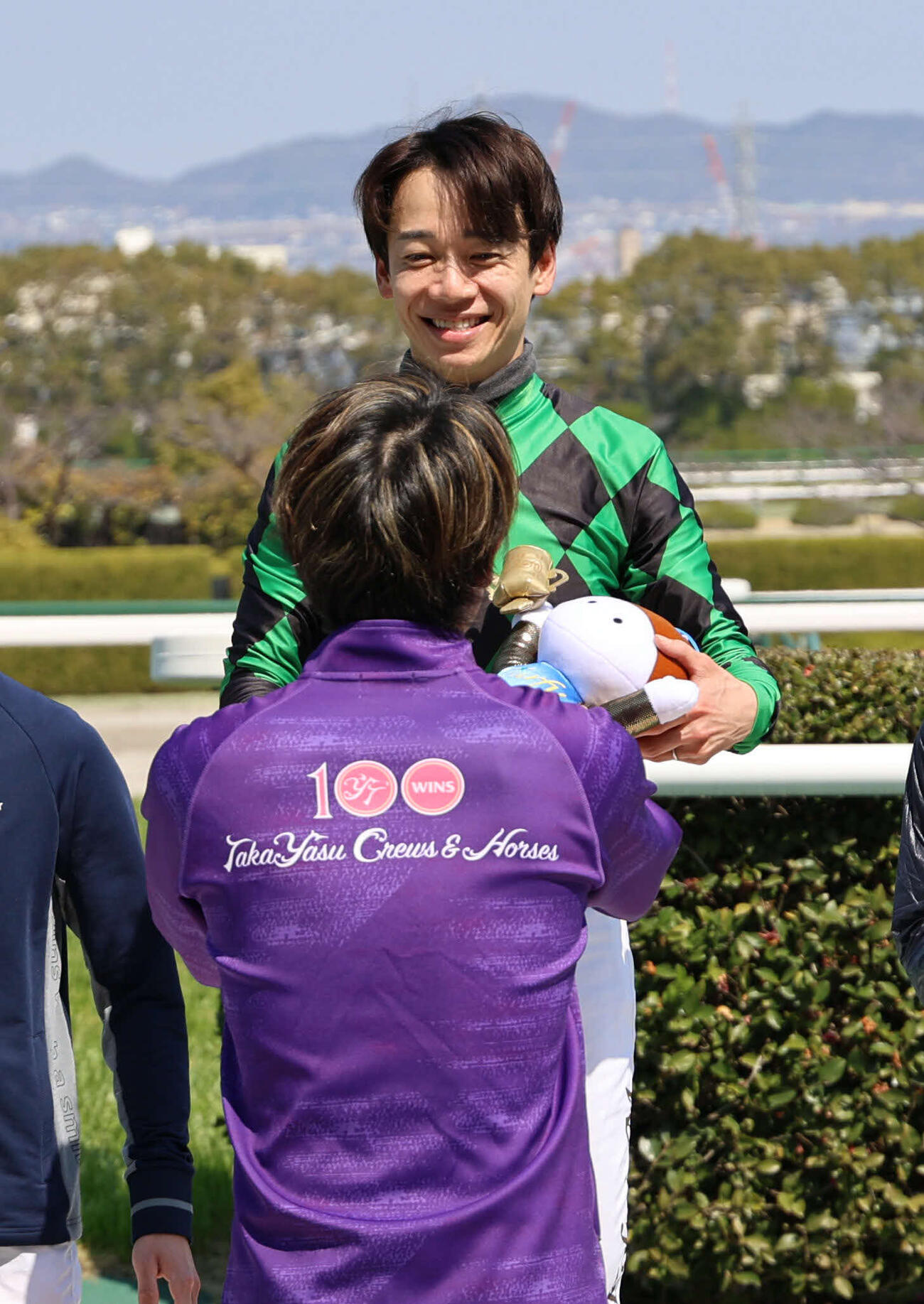 阪神4R、3歳未勝利戦をポッドリプルで制した松山騎手は通算1400勝となり、同期の丸山騎手から記念品を受け取り笑顔（撮影・西尾就之）