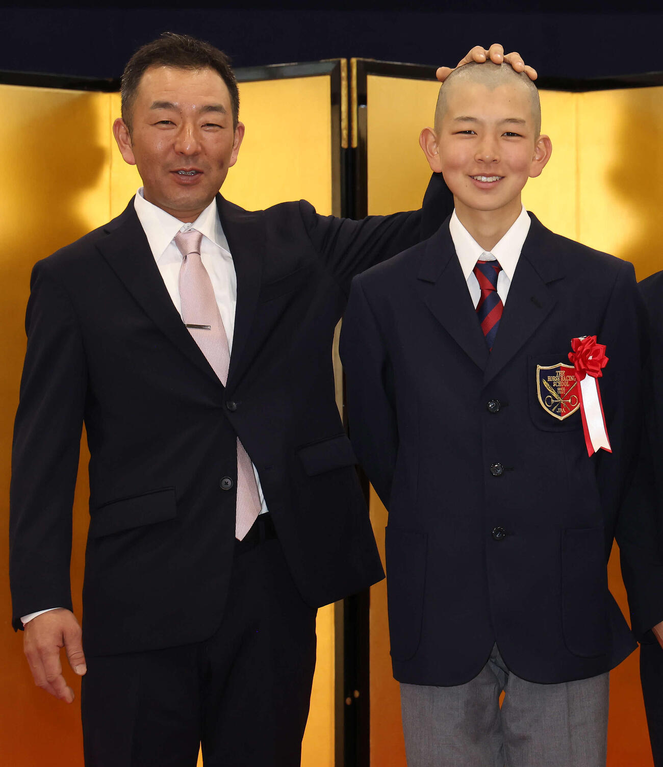 入学式を終えて写真に納まる、勝嵜太資調教助手と文哉君（撮影・丹羽敏通）