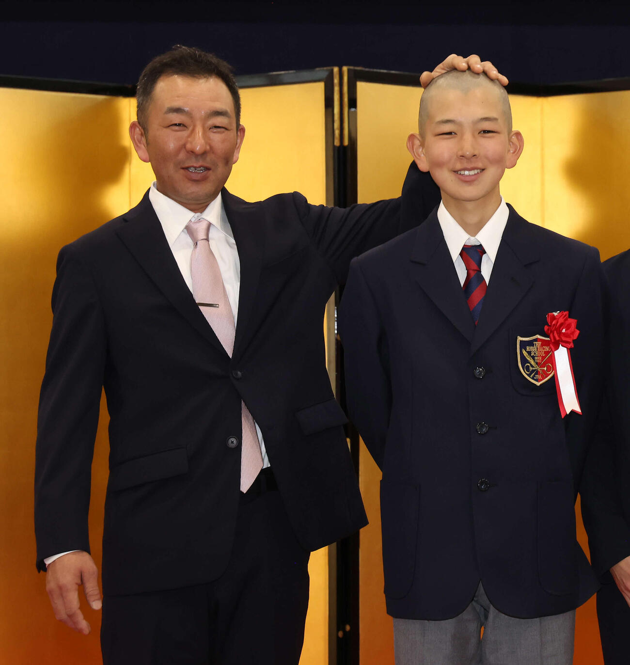 入学式を終えて写真に納まる、勝嵜太資調教助手と文哉君（撮影・丹羽敏通）
