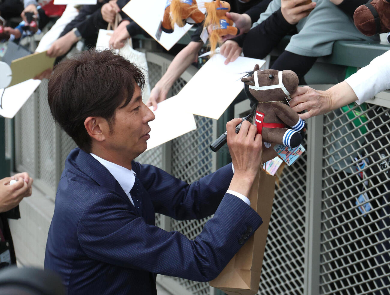 ファンのディープボンドのぬいぐるみにサインする和田竜二元騎手