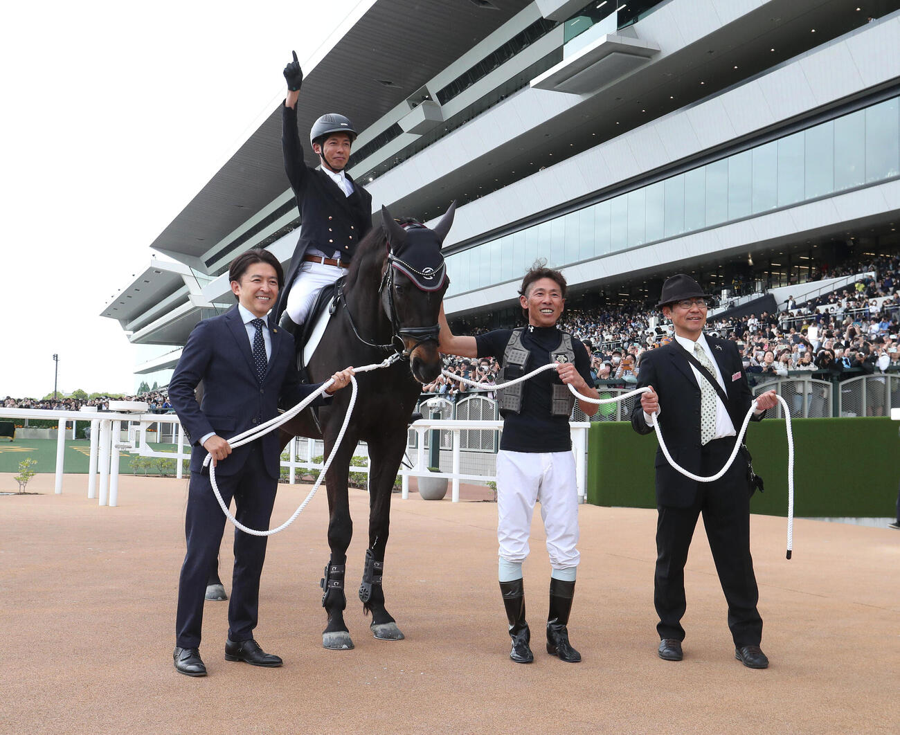 記念写真に納まる、左から福永祐一調教師、ディープボンドの馬上の和田竜二元騎手、古川吉洋騎手、常石勝義元騎手（撮影・白石智彦）