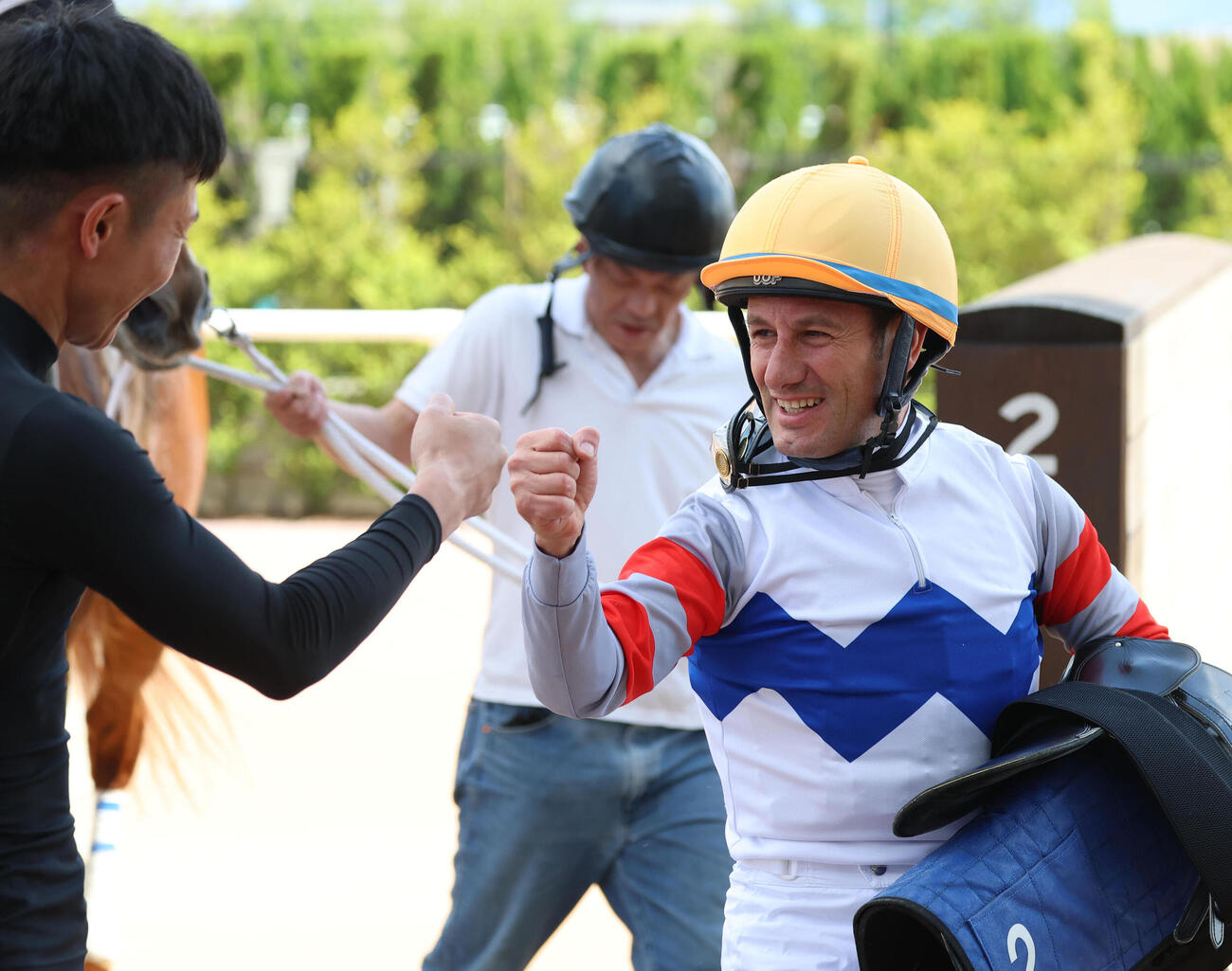 京都7R、帰国後初勝利を挙げ荻野琢騎手（左）とグータッチを交わすミルコ・デムーロ騎手（撮影・白石智彦）
