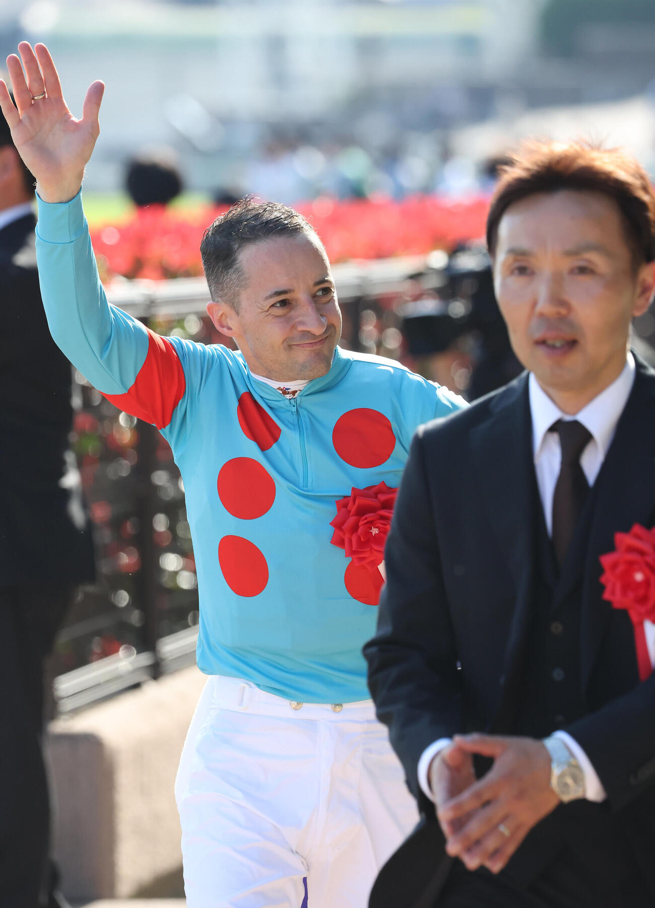 ファンに手を振って表彰式に向かうクリストフ・ルメール騎手。手前は森一誠調教師（撮影・丹羽敏通）