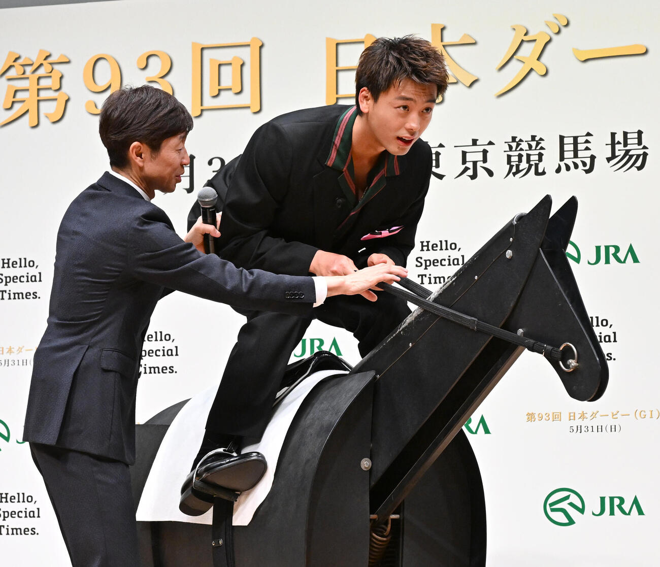 日本ダービーPR発表会で武豊騎手（左）のアドバイスを受けながら木馬にまたがる竹内涼真（撮影・千葉一成）