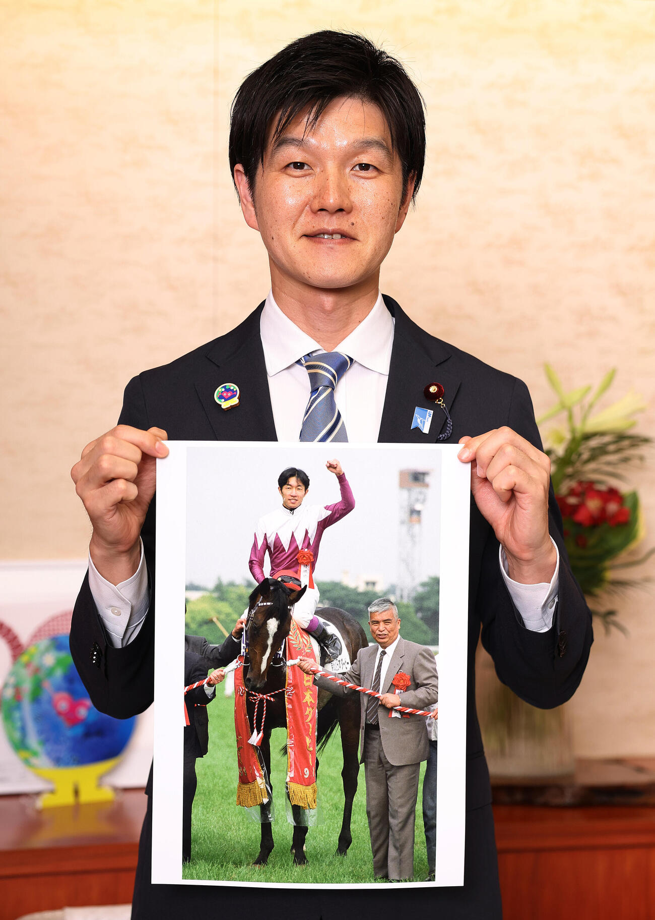 ダービーを制したスペシャルウィークの写真を手にする鈴木憲和農林水産大臣（撮影・野上伸悟）