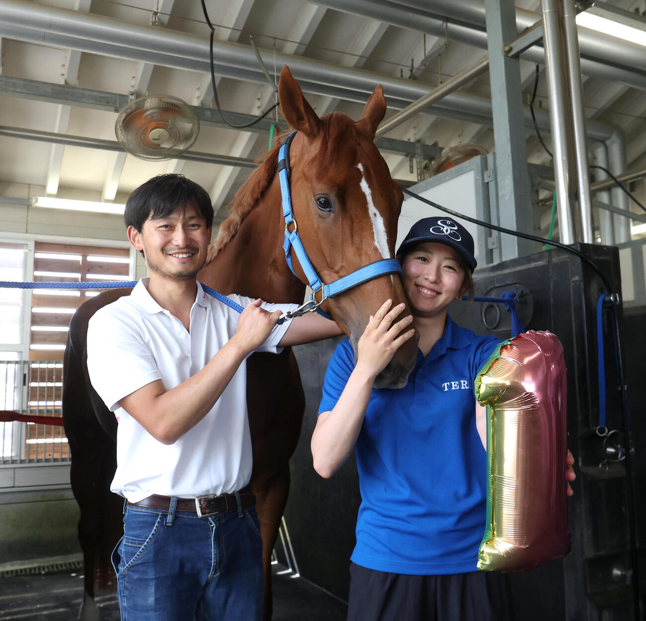 凱旋した今村聖奈騎手と記念写真に納まるジュウリョクピエロと担当の佐々木邦幸調教助手（左）