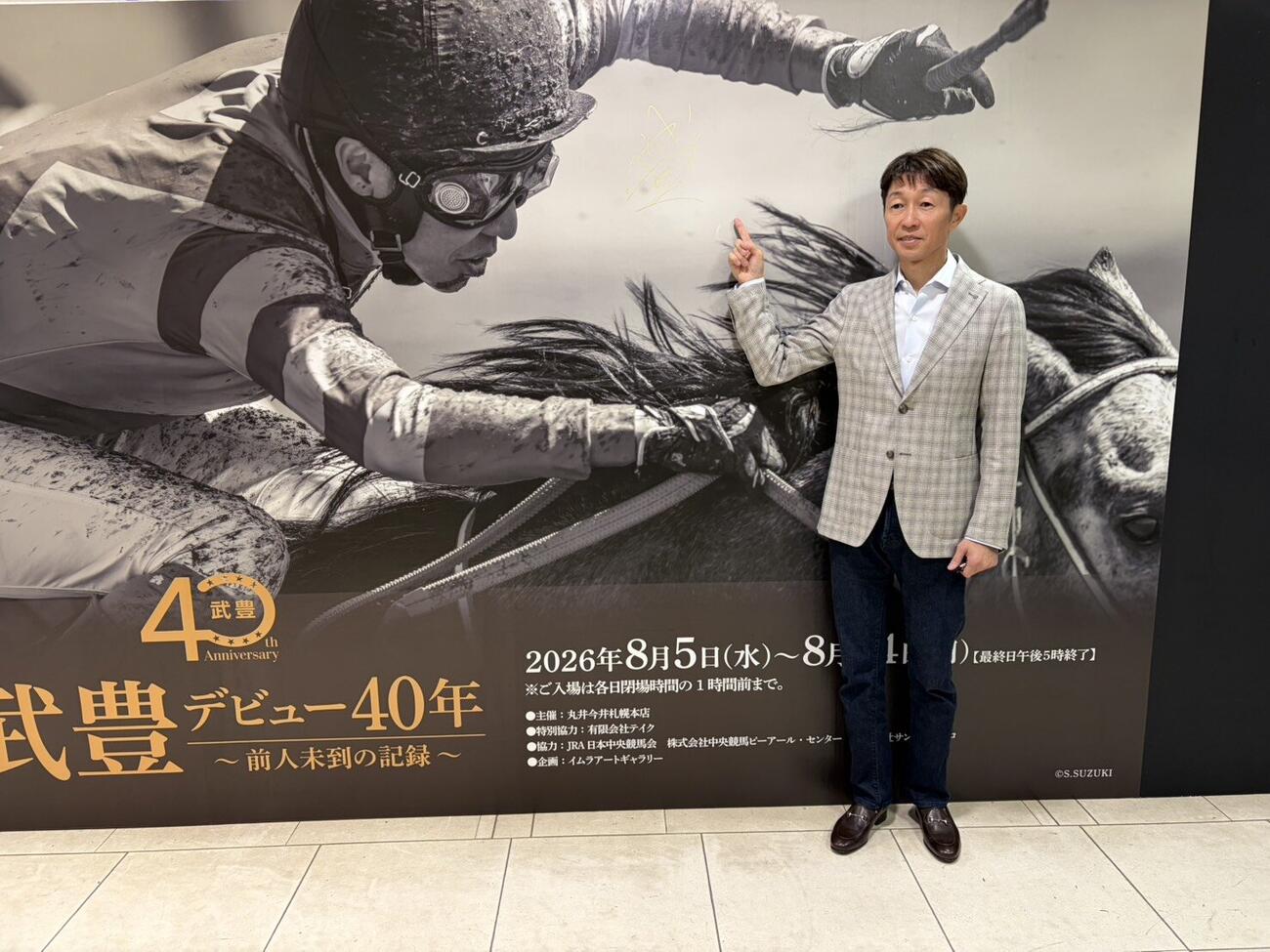入り口のサインを指す武豊騎手