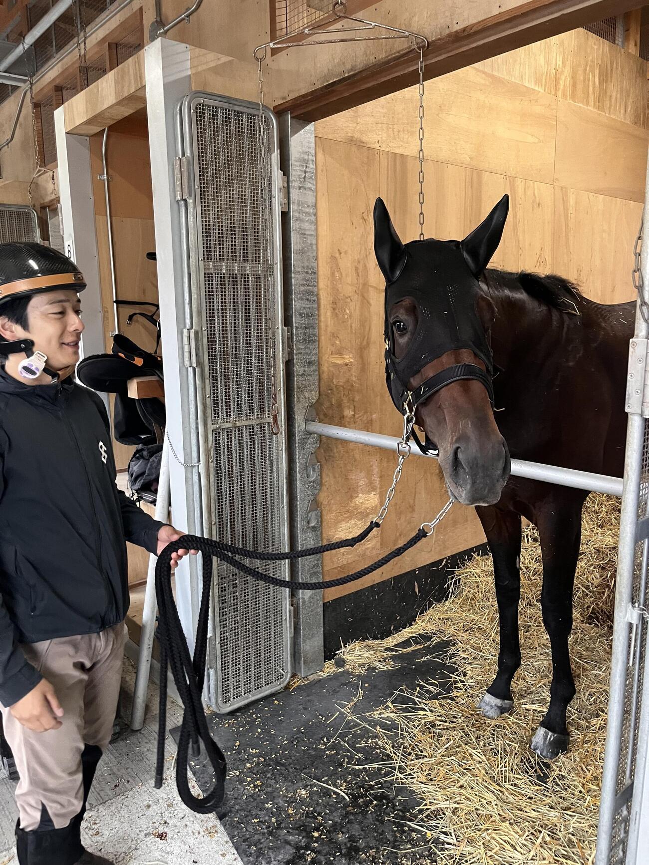札幌2歳Sへ出走を予定するショウナンガレオンは札幌競馬場内の馬房から顔を出す。左は関本助手