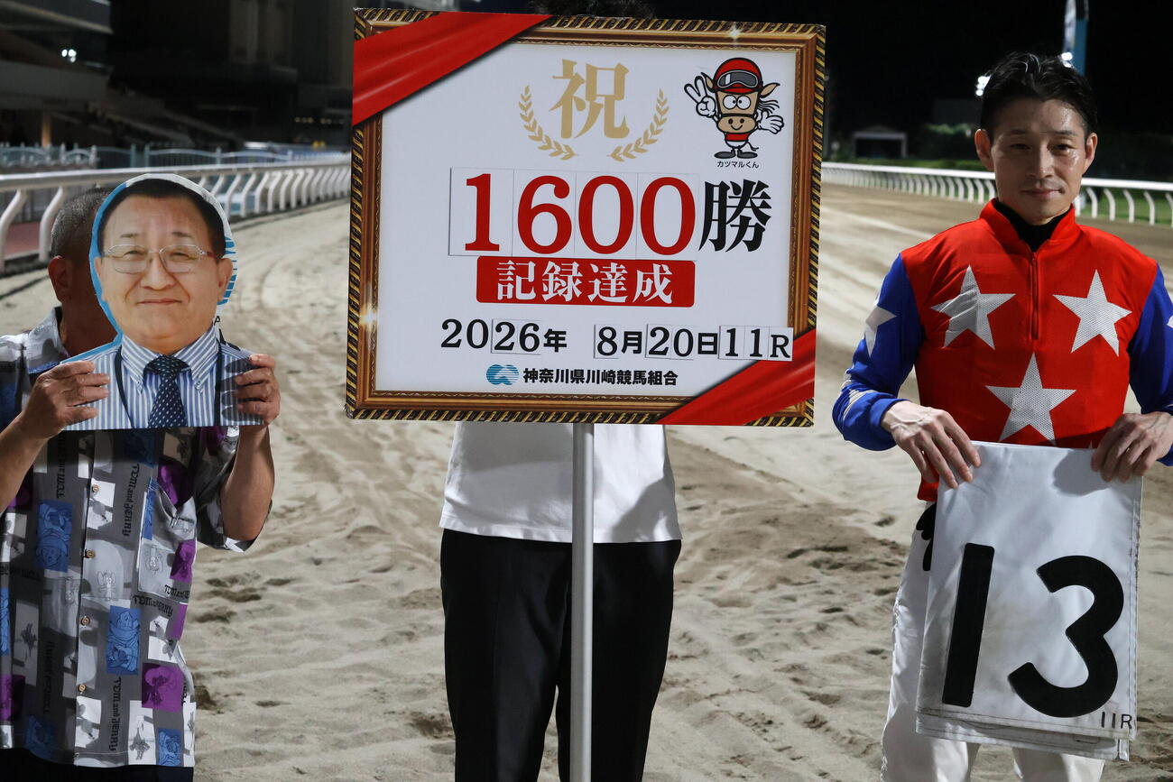 地方競馬通算1600勝を達成した内田調教師の写真を持つ福井調教師補佐（左）と御神本訓史騎手