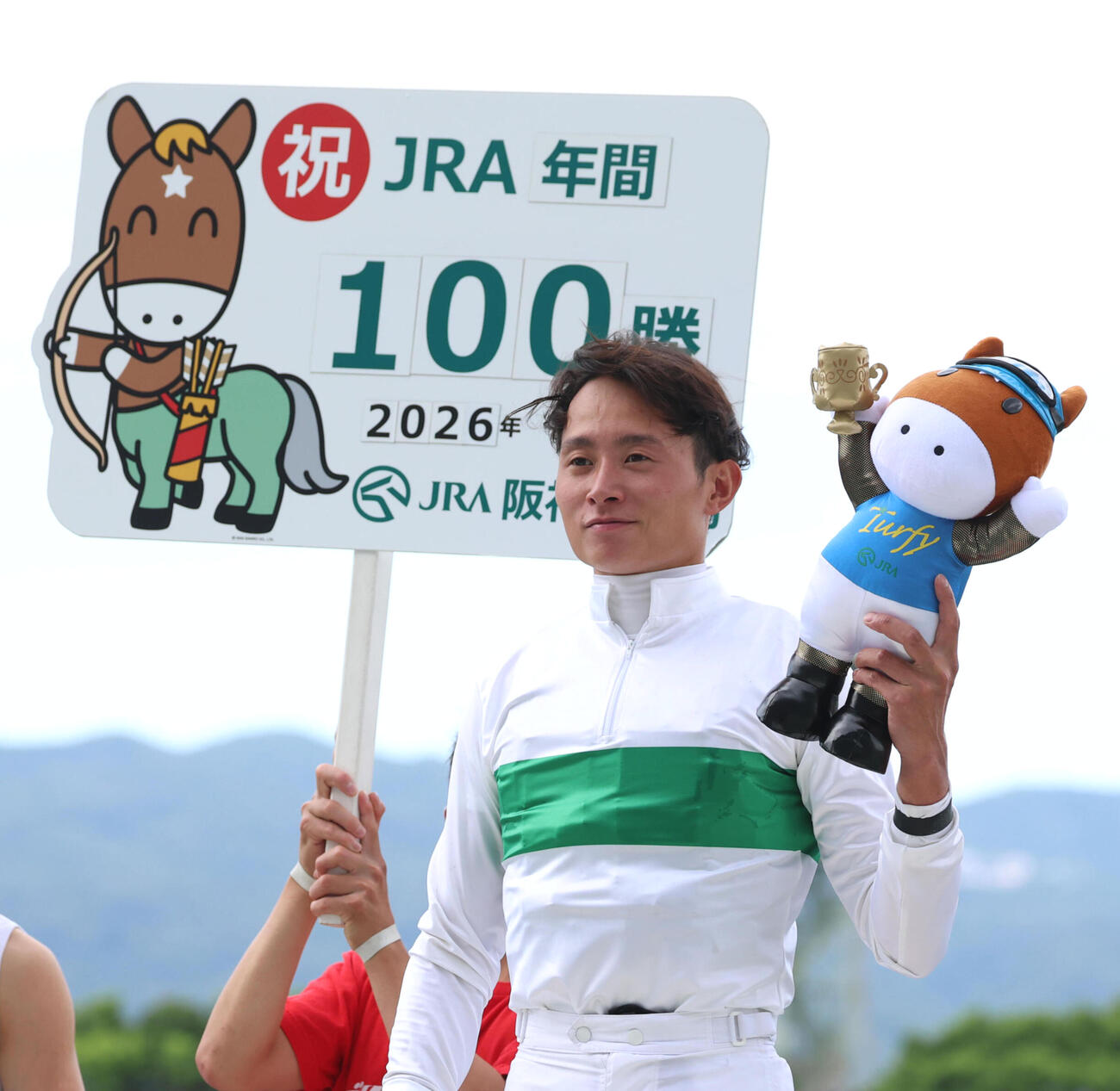 JRA年間100勝を達成し笑顔でターフィー人形を掲げる岩田望来騎手（撮影・白石智彦）