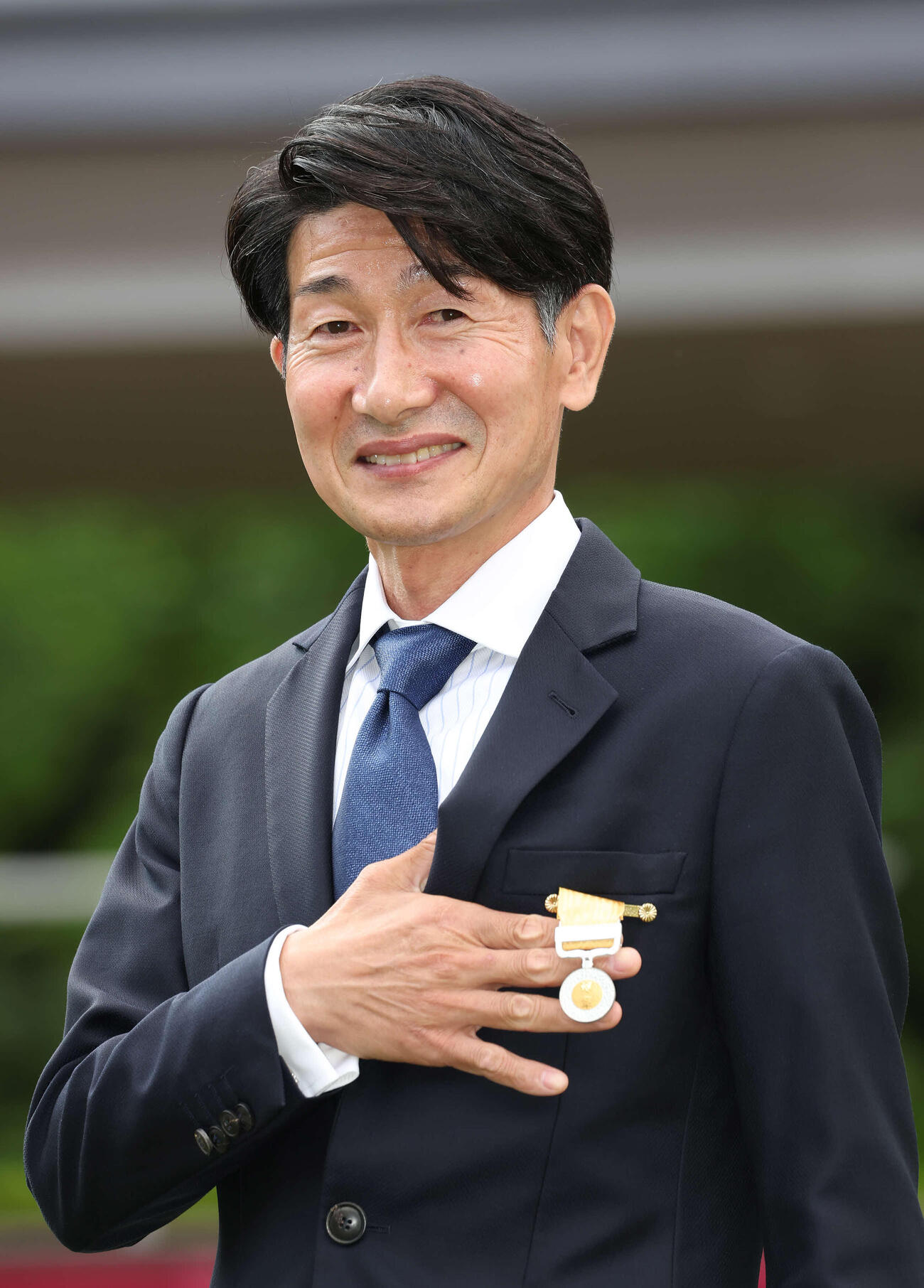 22年5月22日、受賞した黄綬褒章をカメラに向ける柴田善臣騎手