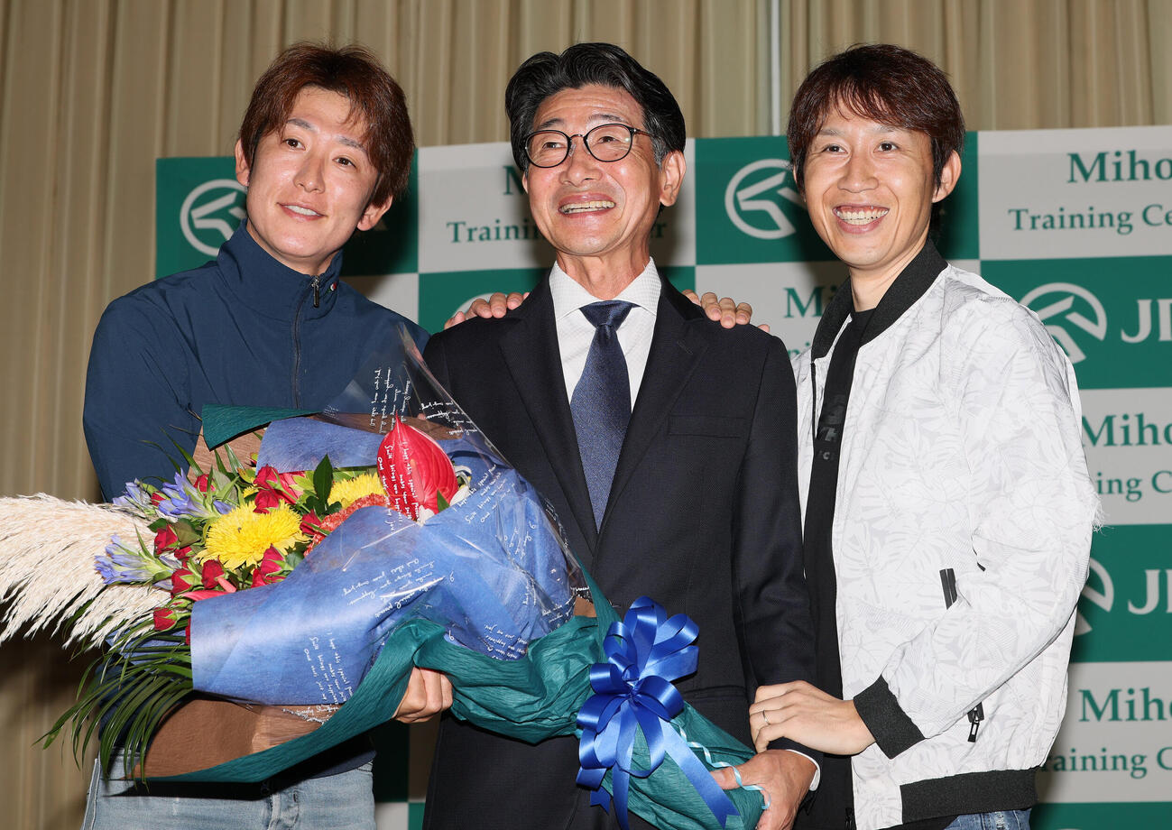 花束を手に写真に納まる柴田善臣騎手（中央）。左は丸山元気騎手、右は田辺裕信騎手（撮影・丹羽敏通）