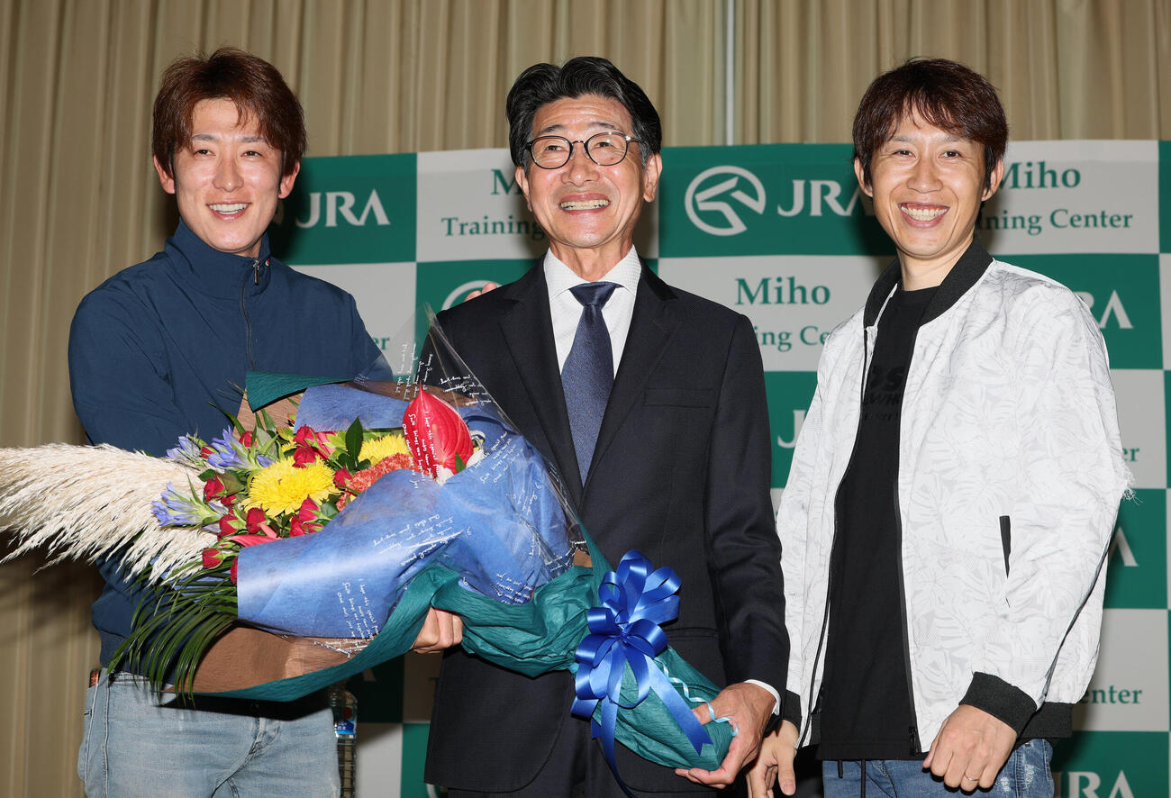 16日、引退記者会見で花束を手に写真に納まる柴田善臣騎手（中央）。左は丸山元気騎手、右は田辺裕信騎手
